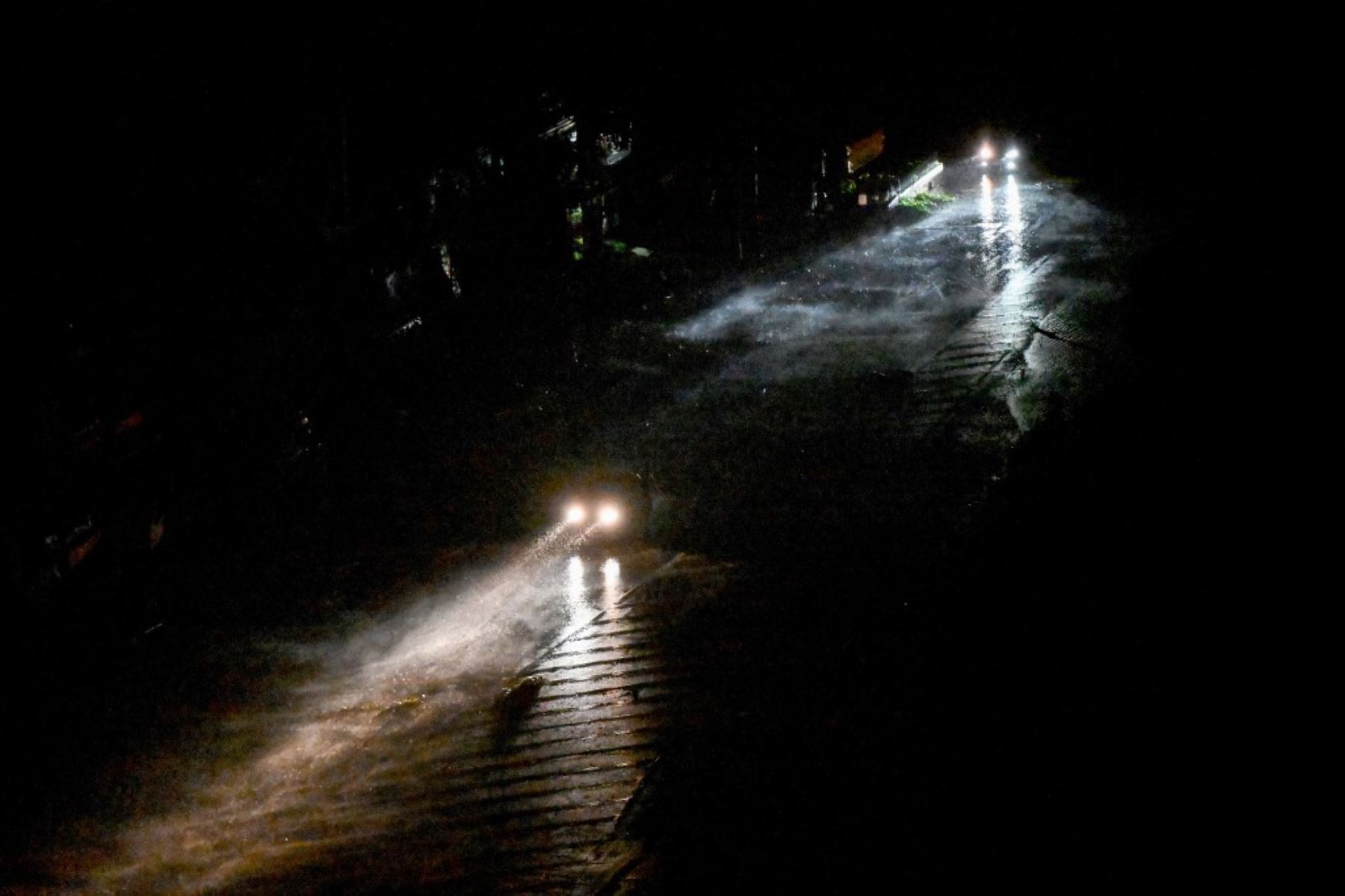 En esta imagen, tomada el 25 de agosto de 2025, se muestran vehículos circulando en medio de cortes de electricidad debido a las fuertes lluvias y vientos en la ciudad de Vinh, provincia de Nghe An, en Vietnam, tras la llegada del tifón Kajiki. Foto: AFP