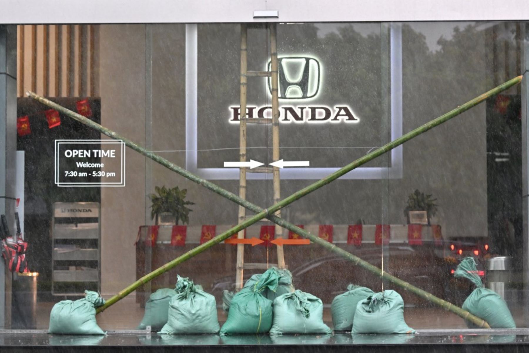 La entrada de un concesionario de automóviles se ve reforzada con sacos de arena y estacas de bambú en la ciudad de Vinh, provincia de Nghe An, el 25 de agosto de 2025, antes de que el tifón Kajiki tocara tierra en Vietnam. Decenas de miles de residentes fueron evacuados de la costa de Vietnam. Foto: AFP