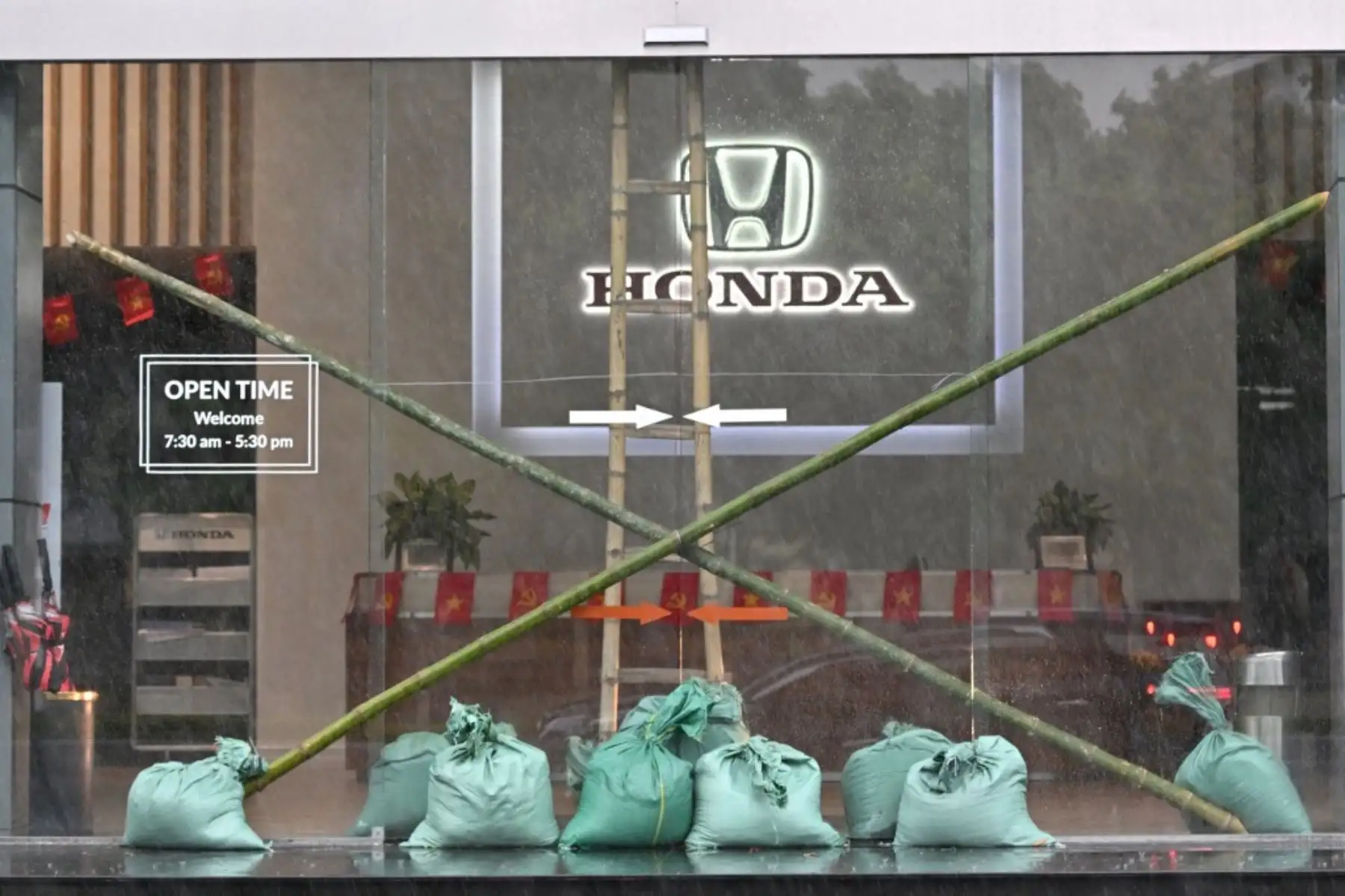 La entrada de un concesionario de automóviles se ve reforzada con sacos de arena y estacas de bambú en la ciudad de Vinh, provincia de Nghe An, el 25 de agosto de 2025, antes de que el tifón Kajiki tocara tierra en Vietnam. Decenas de miles de residentes fueron evacuados de la costa de Vietnam. Foto: AFP
