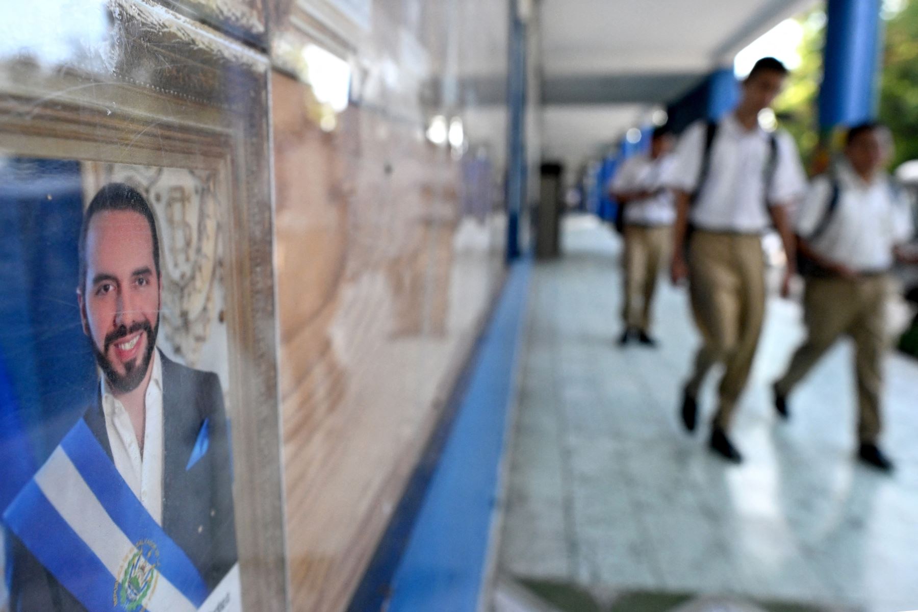 Estudiantes salvadoreños pasan junto a una foto del presidente Bukele en el Instituto Técnico Industrial Nacional. Foto: AFP