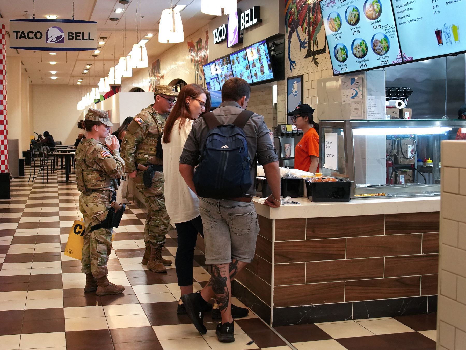 Soldados de la Guardia Nacional, armados con pistolas, esperan para recoger un pedido de comida en el patio de comidas de Union Station  en Washington, D. C. AFP