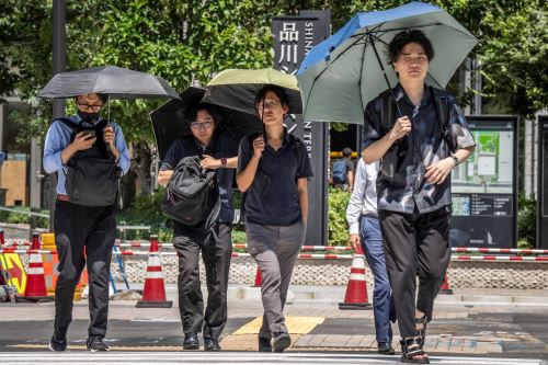 Ciudadanos japoneses caminan con sombrillas en un día caluroso en Tokio, el 27 de agosto de 2025. Foto: AFP
