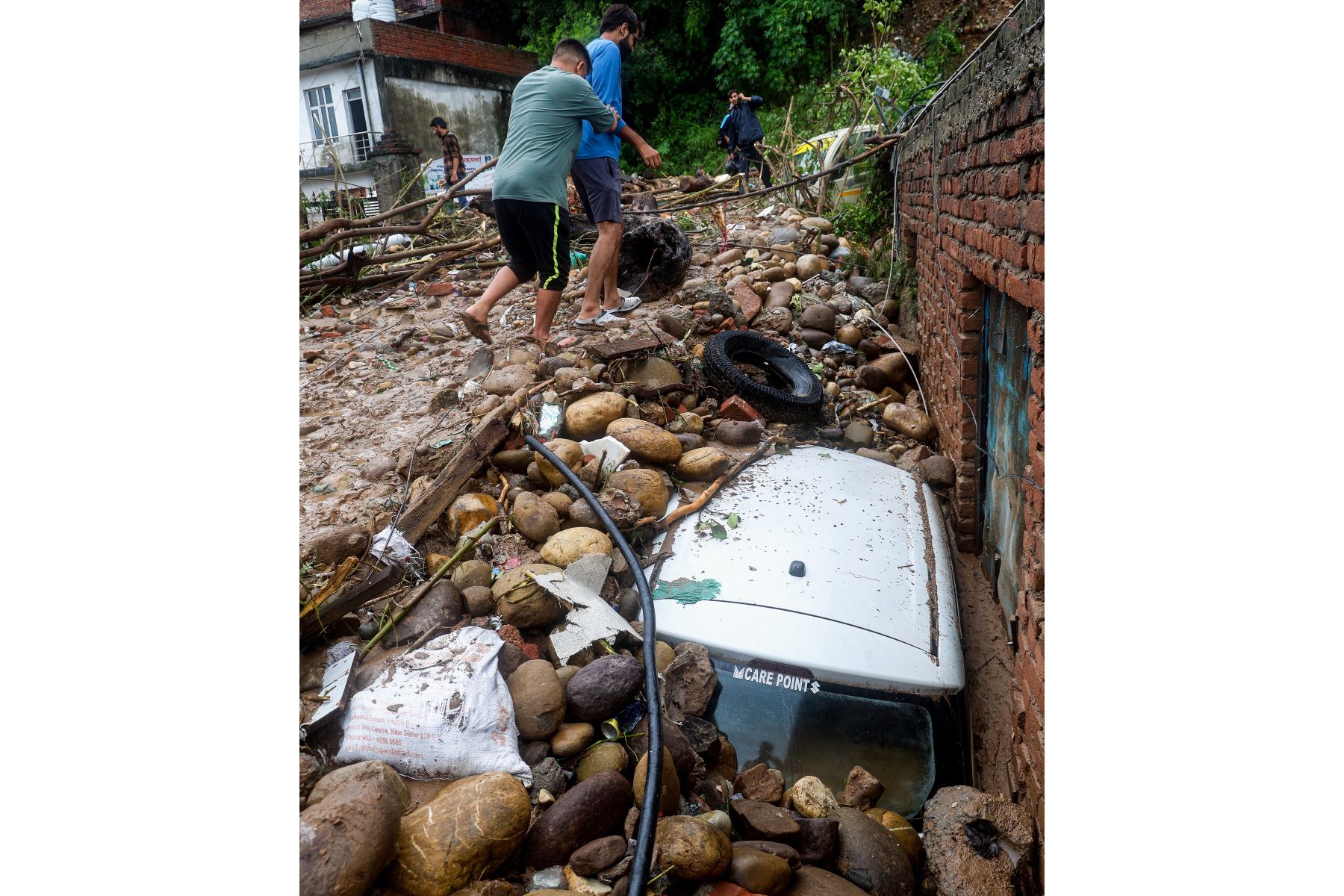 Los residentes caminan junto a un vehículo dañado golpeado por rocas después de que fuertes lluvias provocarán inundaciones repentinas en Jammu.
Foto: AFP