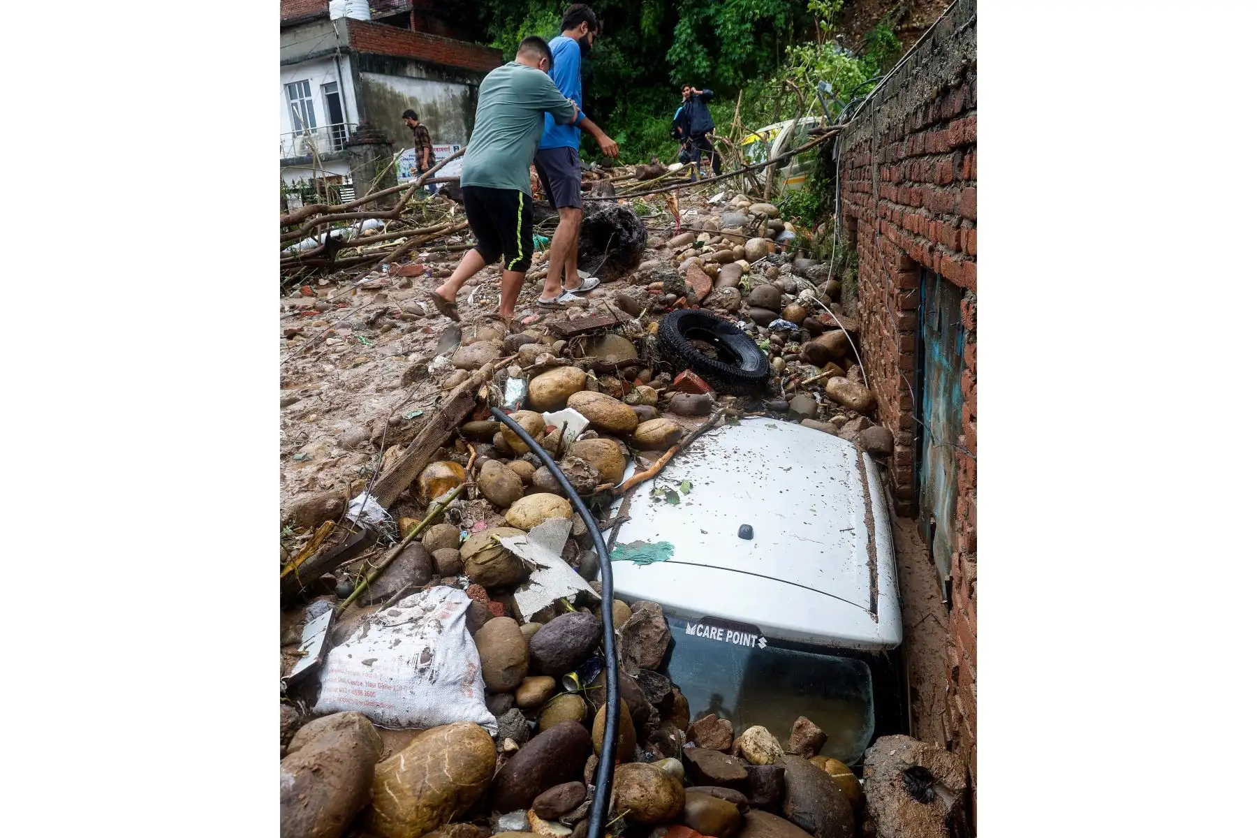 Los residentes caminan junto a un vehículo dañado golpeado por rocas después de que fuertes lluvias provocarán inundaciones repentinas en Jammu.
Foto: AFP