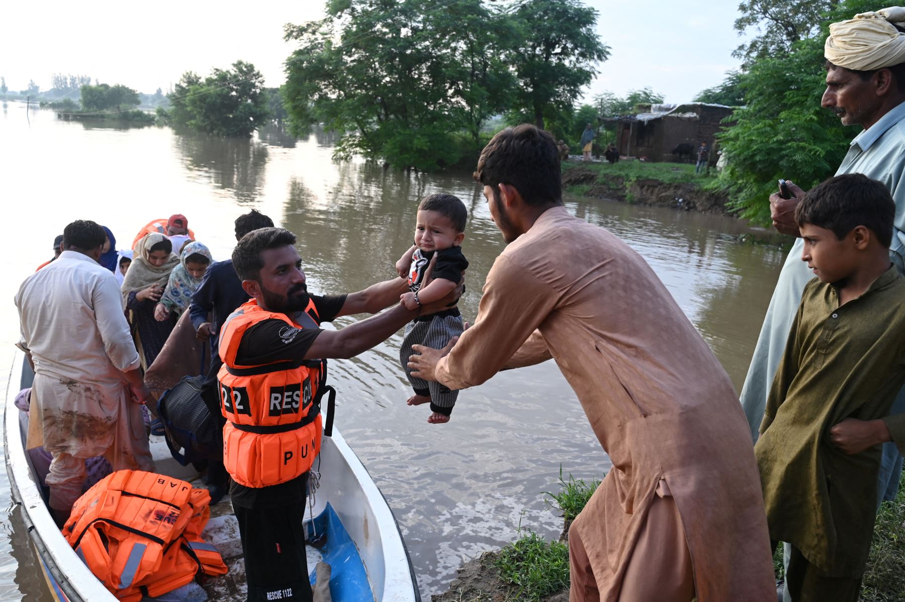 Los rescatistas en una pequeña embarcación entregan a un bebé mientras evacúan a los residentes de la zona inundada de Narowal, una ciudad de la provincia de Punjab. AFP