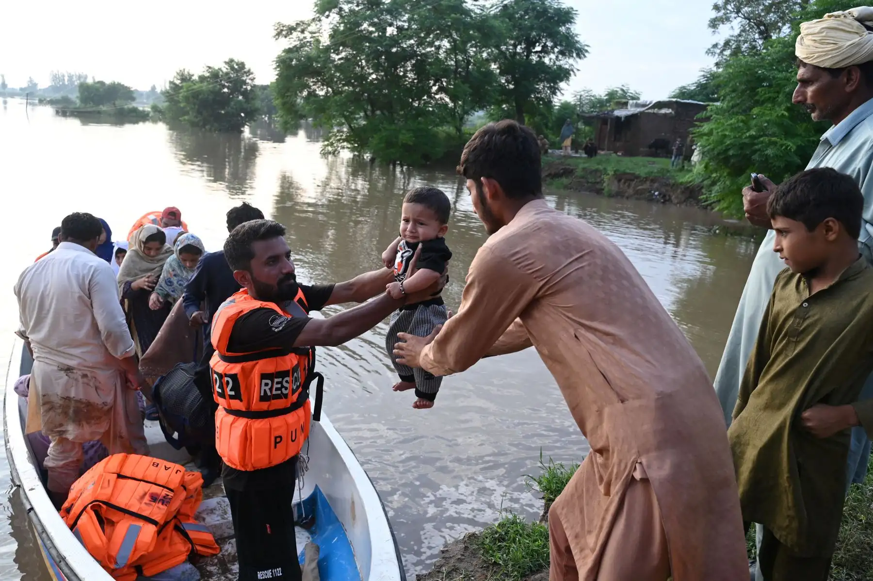 Los rescatistas en una pequeña embarcación entregan a un bebé mientras evacúan a los residentes de la zona inundada de Narowal, una ciudad de la provincia de Punjab. AFP