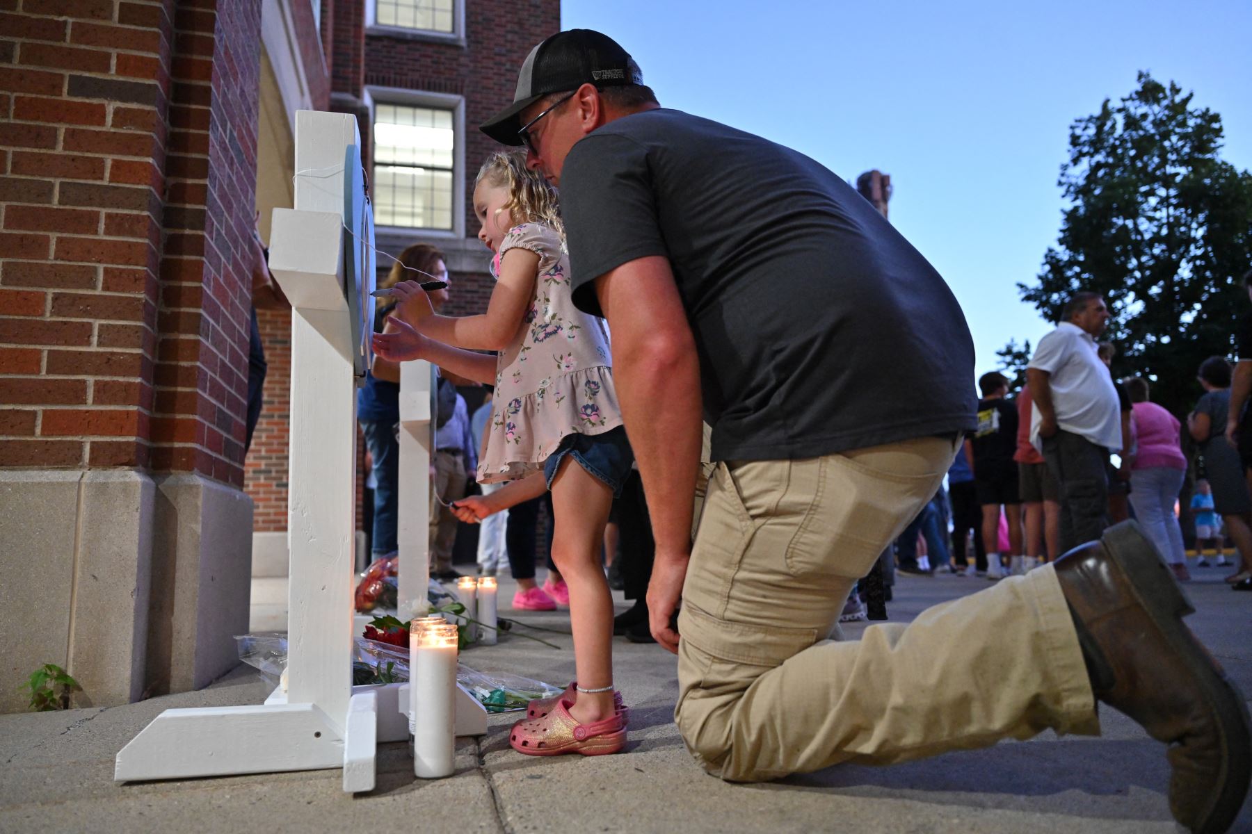 Dolientes firman cruces conmemorativas durante una vigilia en la Academia de los Santos Ángeles en Richfield, Minnesota, en memoria de las víctimas del tiroteo masivo en la Iglesia y Escuela Católica de la Anunciación en Minneapolis, donde dos personas murieron y 17 resultaron heridas a manos de un tirador . Foto: AFP