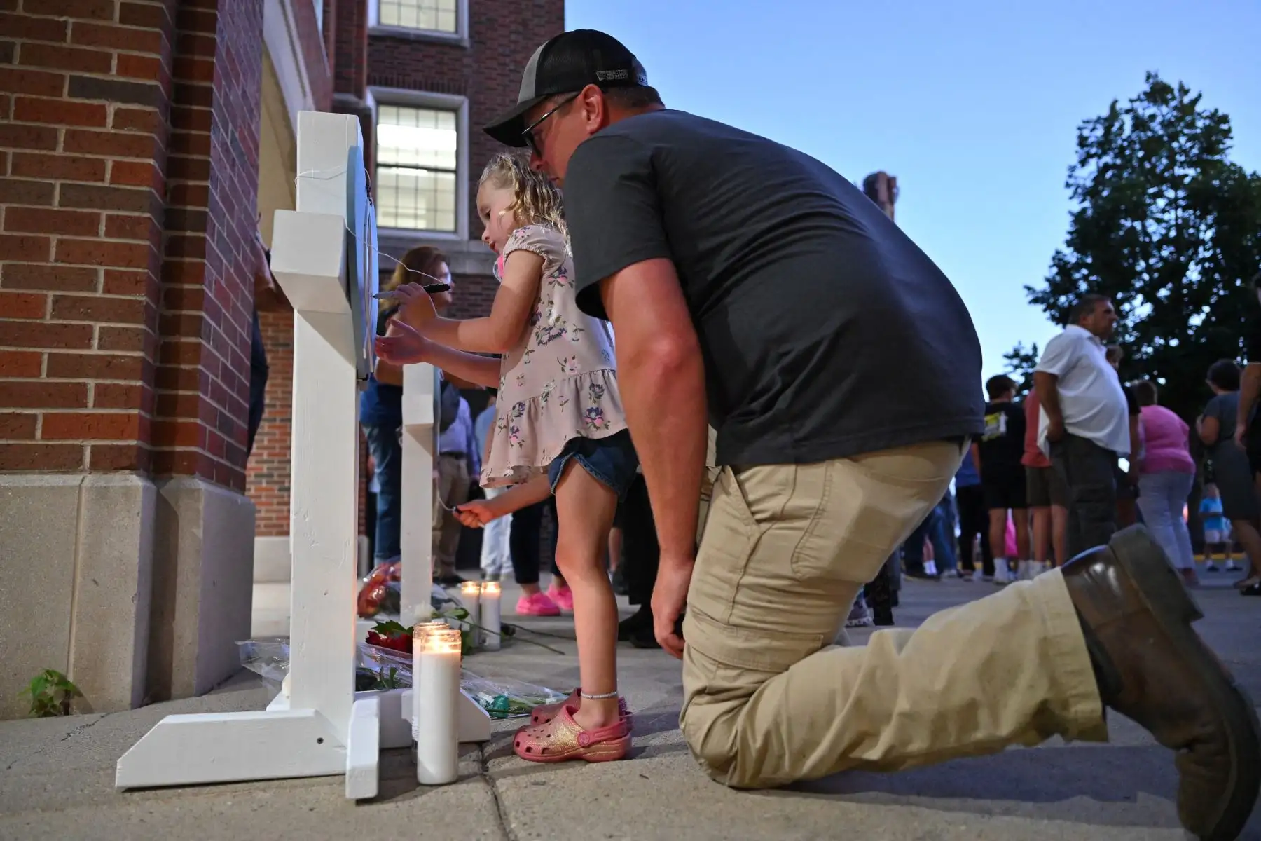 Dolientes firman cruces conmemorativas durante una vigilia en la Academia de los Santos Ángeles en Richfield, Minnesota, en memoria de las víctimas del tiroteo masivo en la Iglesia y Escuela Católica de la Anunciación en Minneapolis, donde dos personas murieron y 17 resultaron heridas a manos de un tirador . Foto: AFP