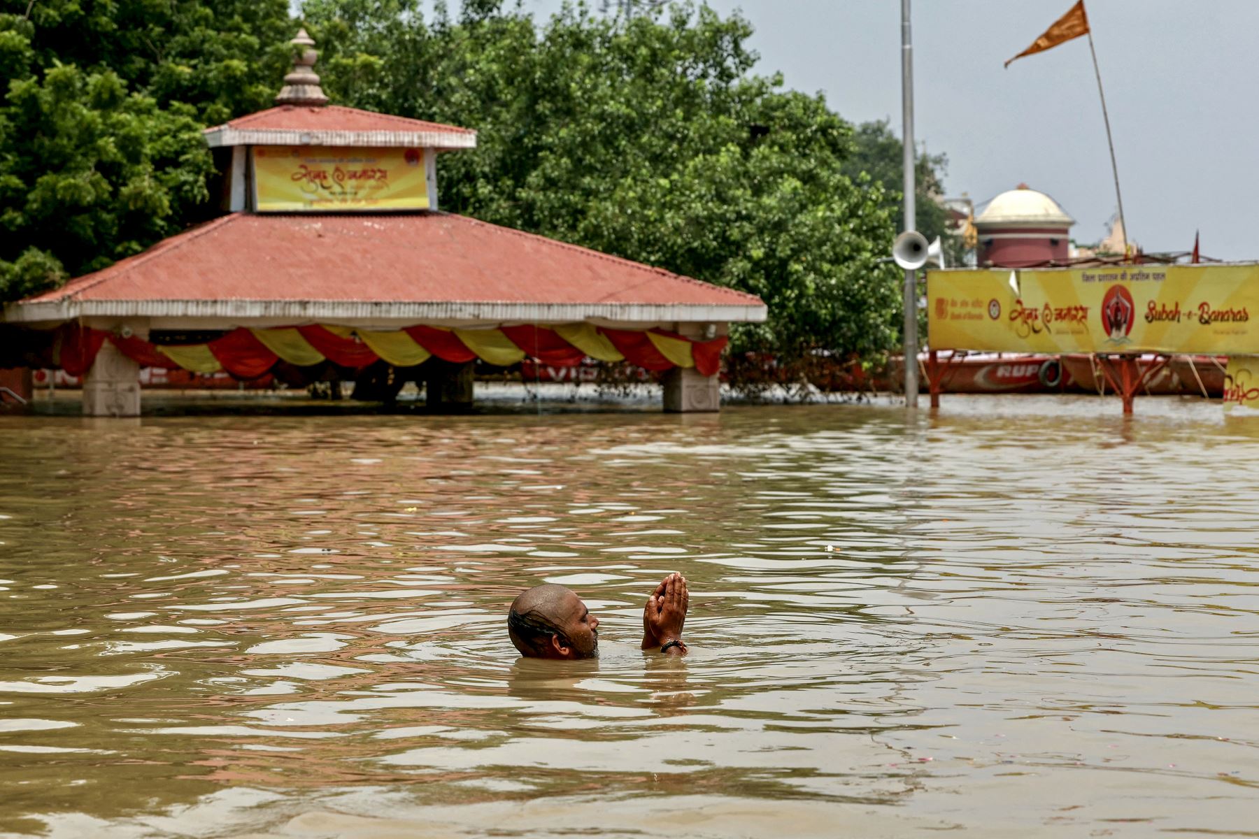 Un hombre reza en el Assi Ghat inundado después de que el nivel del agua del río Ganges volviera a subir debido al impacto aguas arriba en Varanasi. Foto: AFP