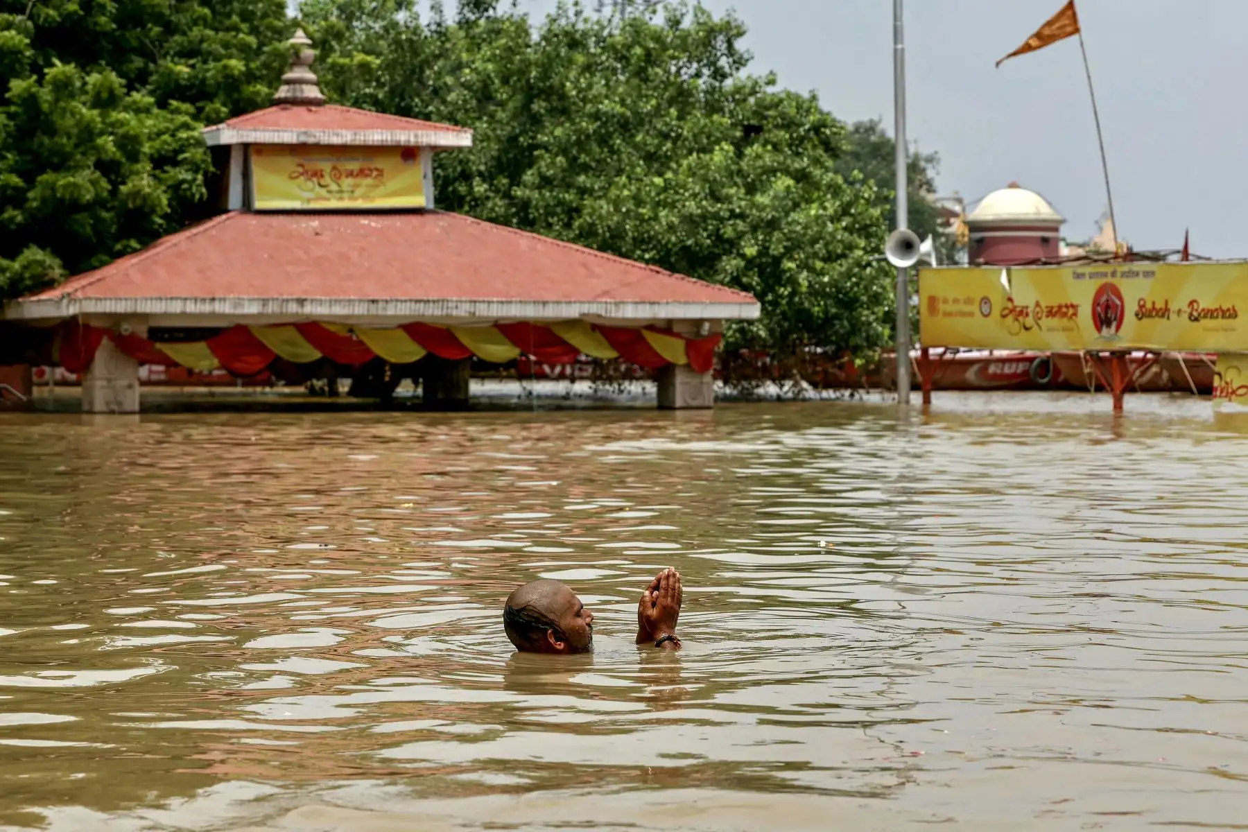 Un hombre reza en el Assi Ghat inundado después de que el nivel del agua del río Ganges volviera a subir debido al impacto aguas arriba en Varanasi. Foto: AFP