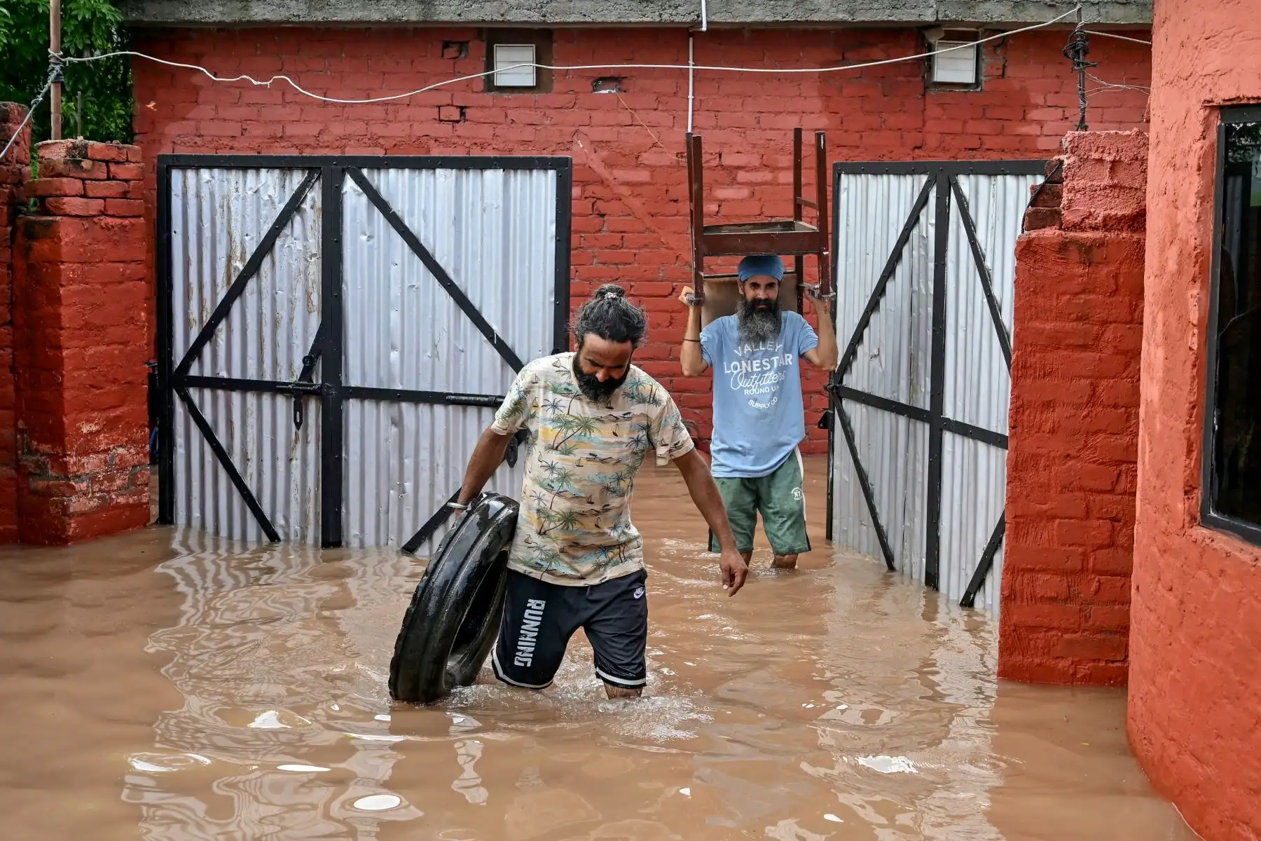 Los residentes, junto con sus pertenencias, evacúan sus hogares inundados después de un aumento en el nivel del agua del río Ravi tras las fuertes lluvias en un pueblo cerca de Ramdas, a unos 45 km de Amritsar.  AFP