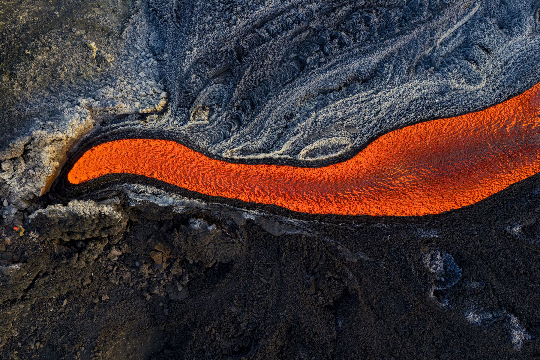Esta vista aérea muestra a un hombre parado cerca de un flujo de lava en el volcán Monte Etna. AFP