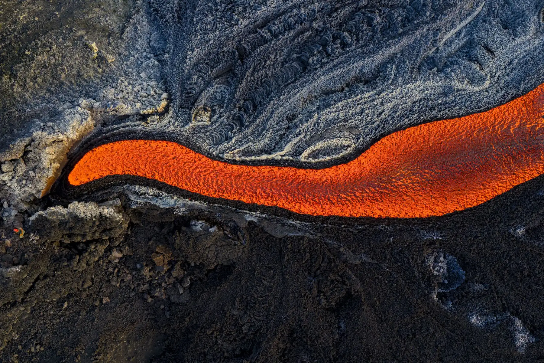 Esta vista aérea muestra a un hombre parado cerca de un flujo de lava en el volcán Monte Etna. AFP