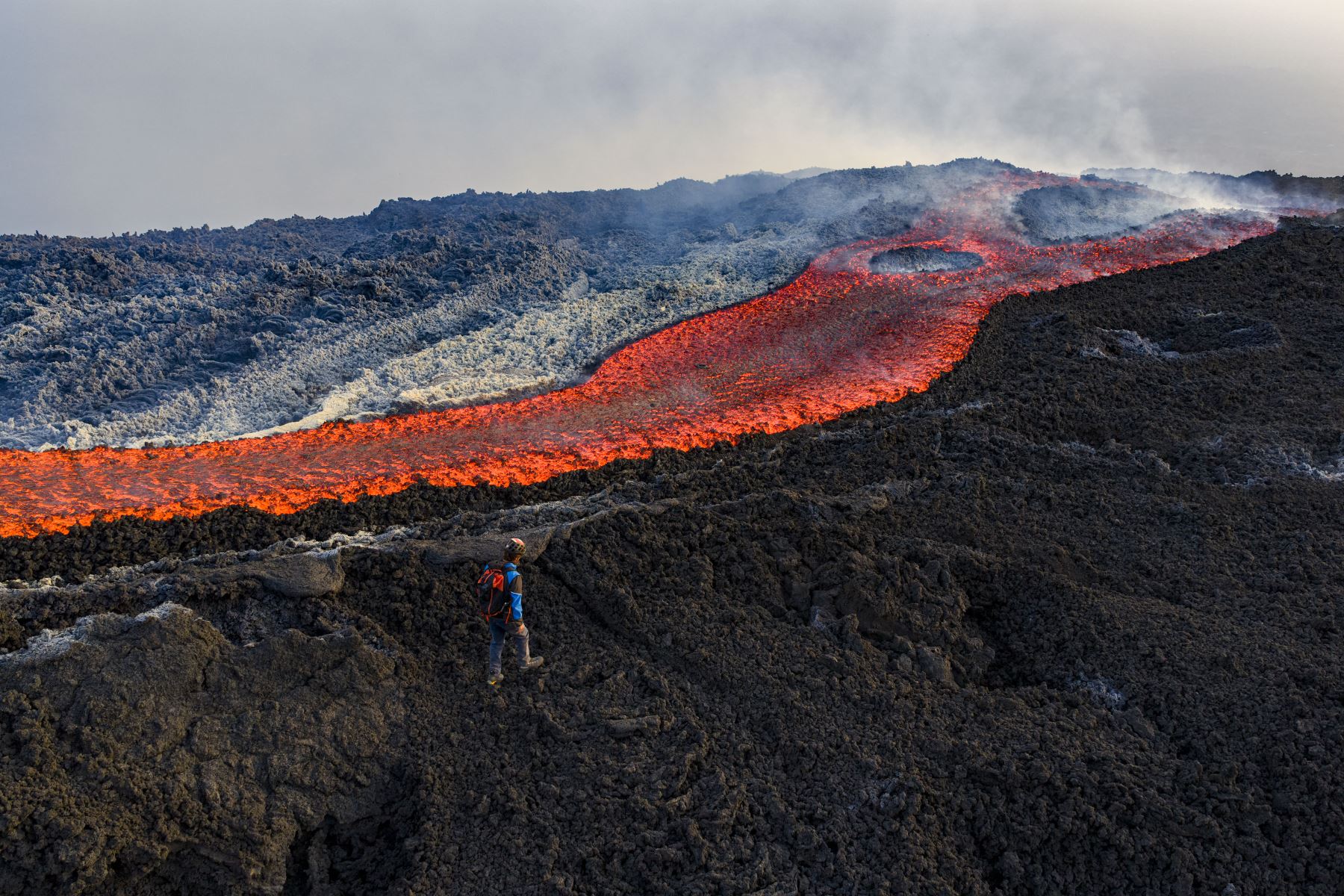 Esta vista aérea muestra a un hombre parado cerca de un flujo de lava en el volcán Monte Etna. AFP