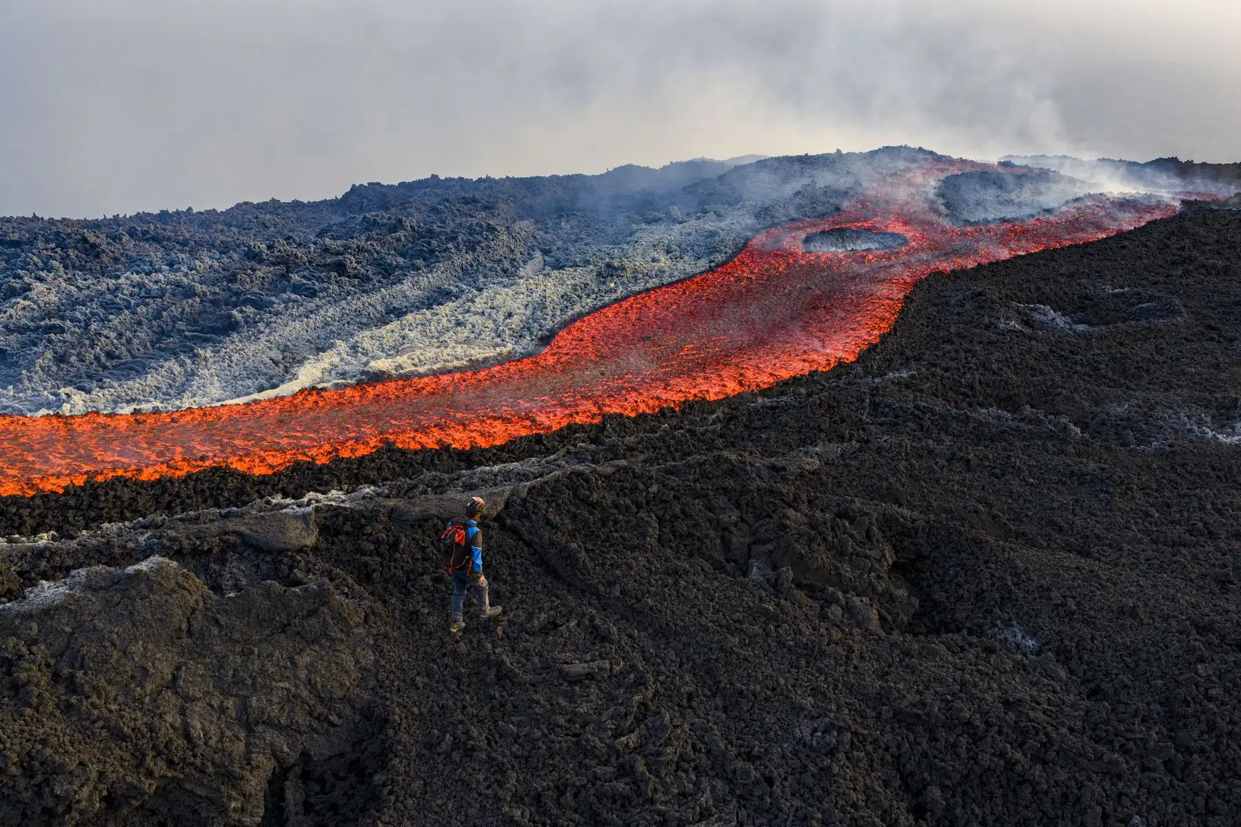 Esta vista aérea muestra a un hombre parado cerca de un flujo de lava en el volcán Monte Etna. AFP