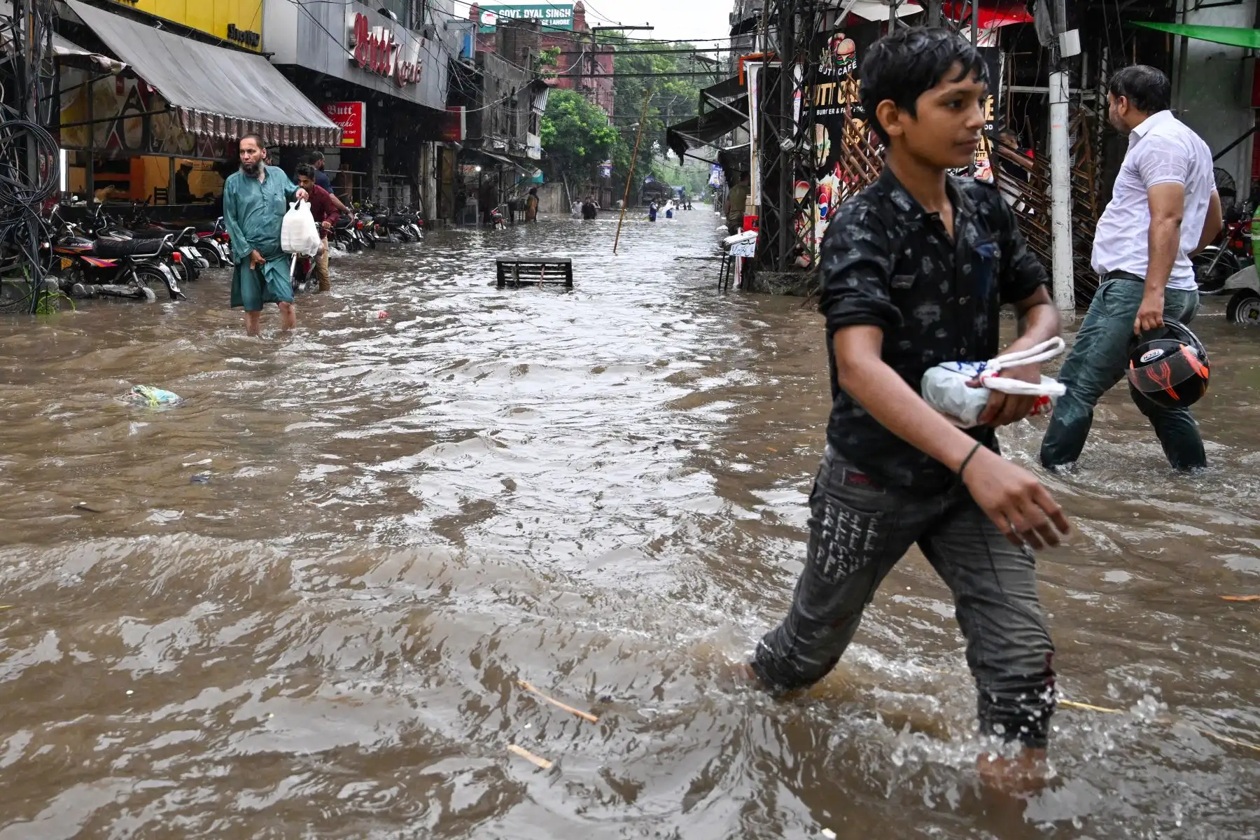 Los viajeros caminan por una carretera inundada en medio de fuertes lluvias en Lahore.
Foto: AFP