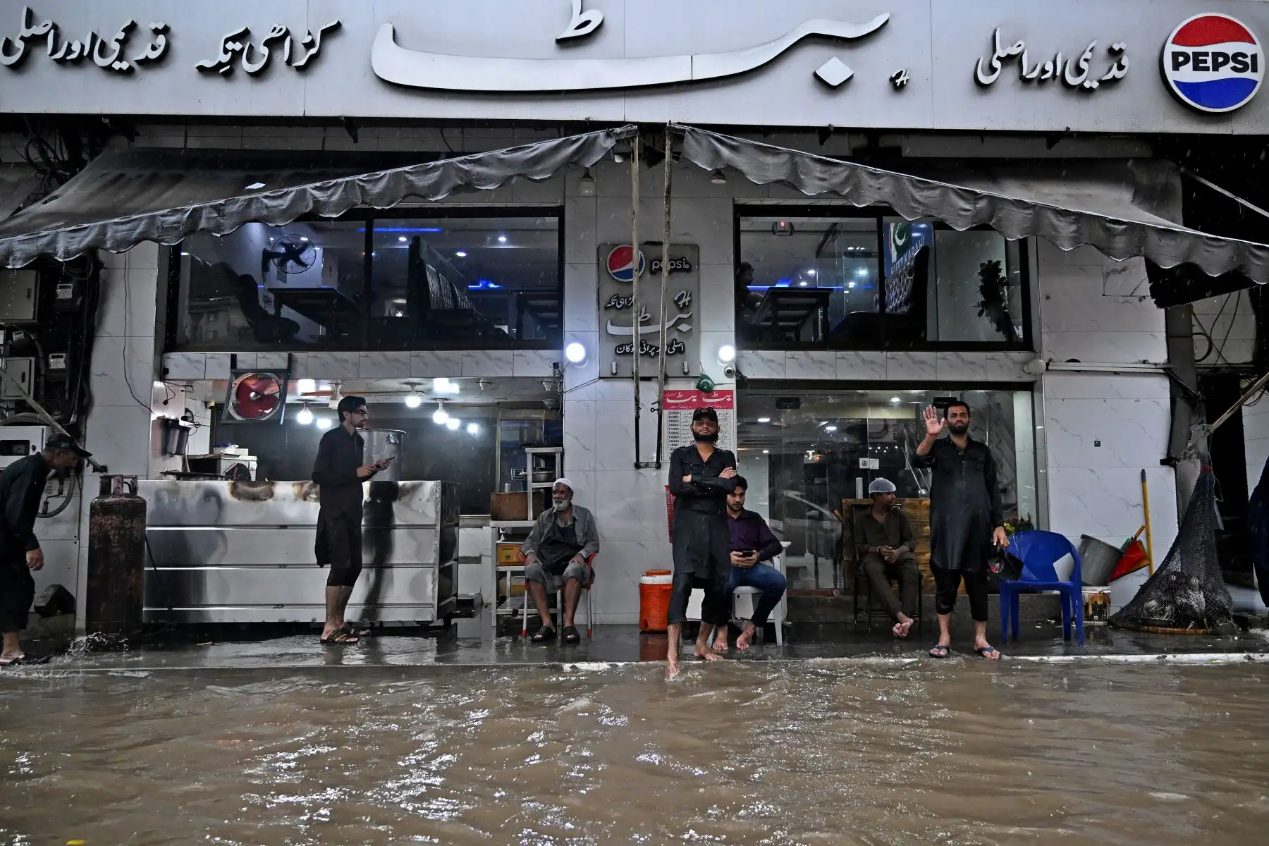 Los camareros están de pie en un restaurante, en medio de una carretera inundada durante fuertes lluvias en Lahore. Las lluvias monzónicas de esta semana hicieron crecer tres ríos transfronterizos que atraviesan la provincia oriental de Pakistán, el corazón agrícola de la nación y hogar de casi la mitad de sus 255 millones de habitantes.
Foto: AFP