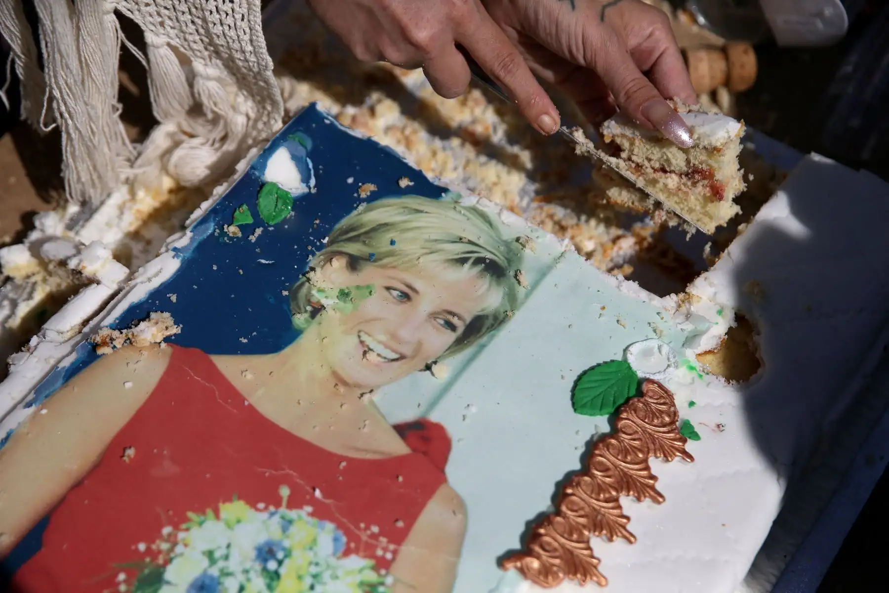 John Loughrey, admirador de la realeza, reparte rebanadas de un pastel adornado con una imagen de Diana, Princesa de Gales, al público reunido frente a una de las puertas del Palacio de Kensington en Londres el 31 de agosto de 2017 para conmemorar el 20.º aniversario de su fallecimiento. Foto: ANDINA/ AFP