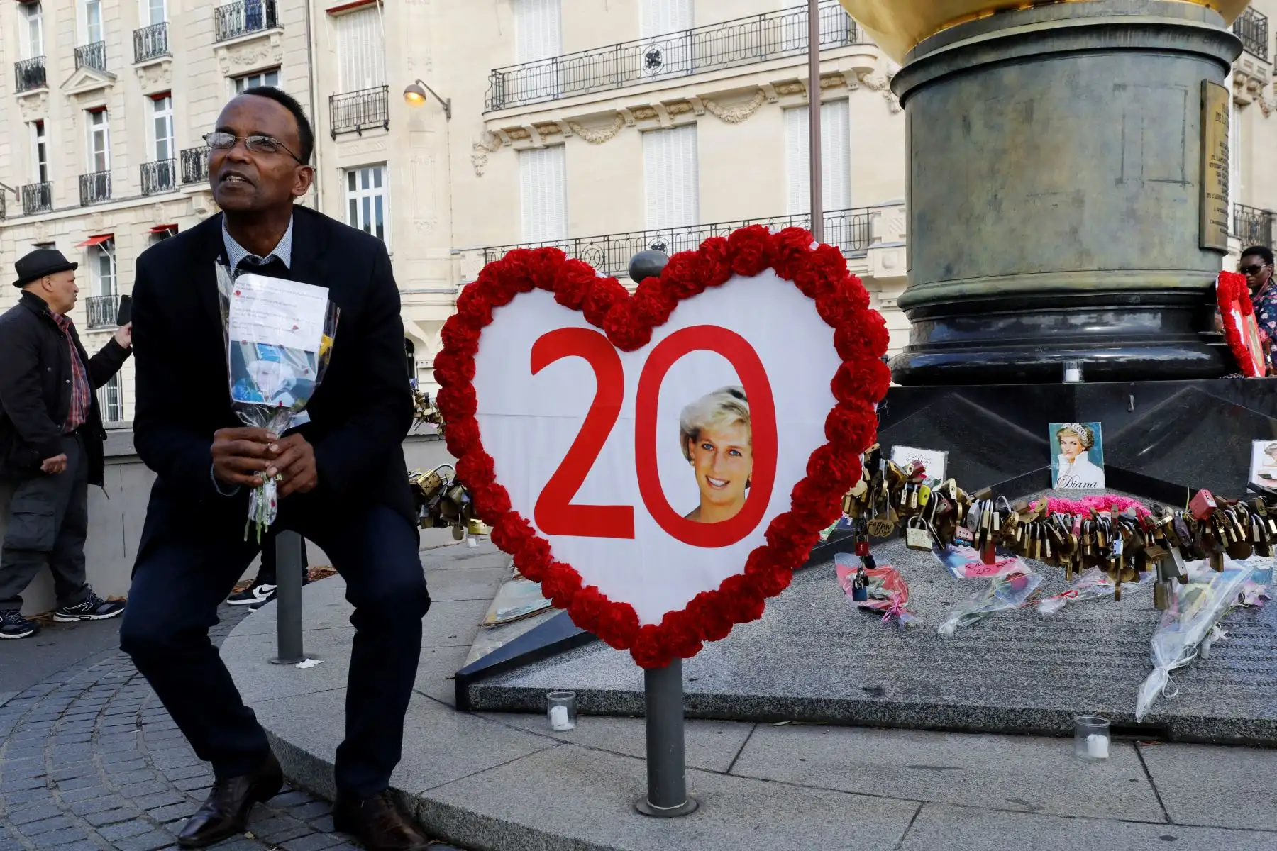 Un hombre se sienta junto a un cartel con forma de calor que conmemora el 20.º aniversario de la muerte de la princesa Diana en el monumento de la Llama de la Libertad, que se convirtió en un monumento no oficial en memoria de la princesa de Gales, fallecida en un accidente de coche en un túnel cercano, sobre el puente de Alma en París el 31 de agosto de 2017. Foto: ANDINA/AFP