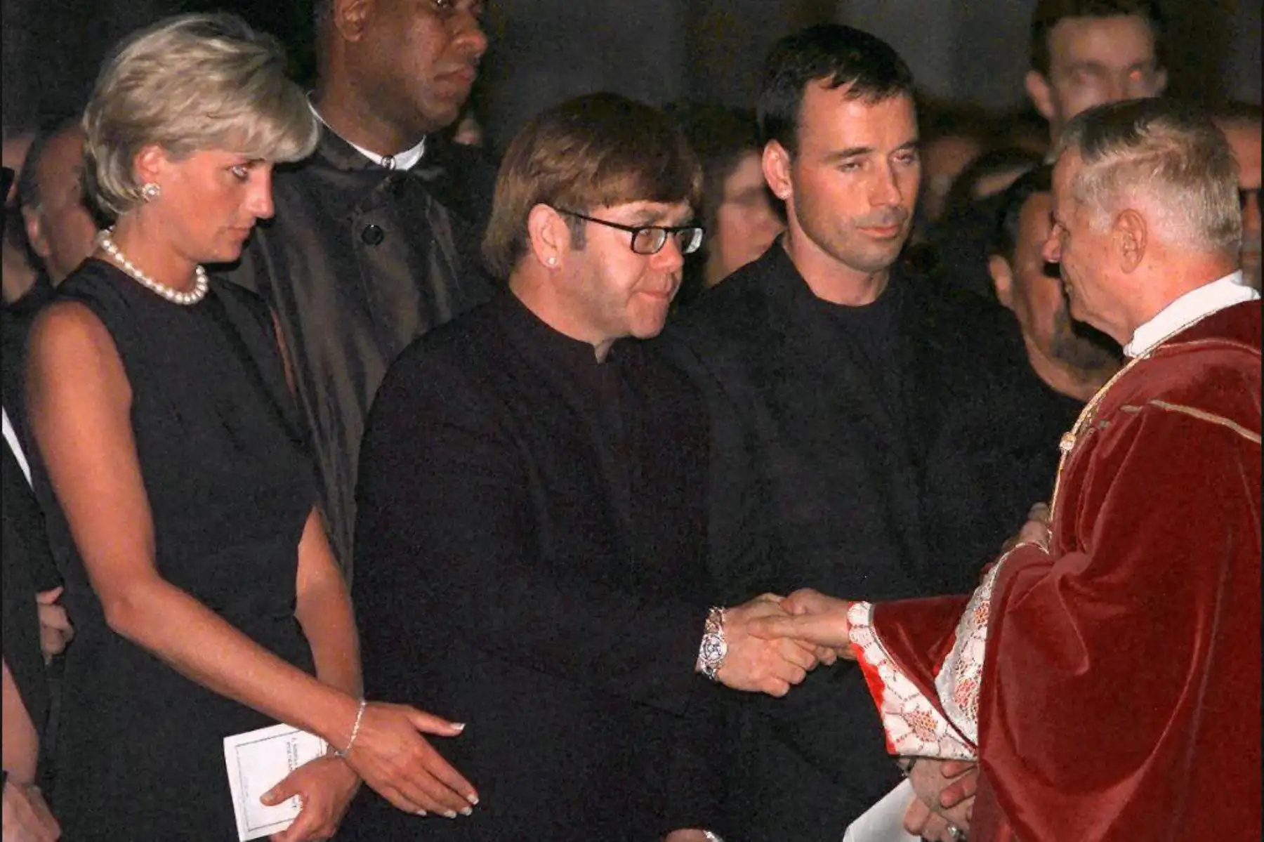 El arcipreste Magio estrecha la mano de la estrella de rock británica Elton John, junto a la princesa Diana durante la misa de réquiem por el diseñador de moda italiano Gianni Versace en el Duomo de Milán el 22 de julio de 1997. Foto: ANDINA/ AFP