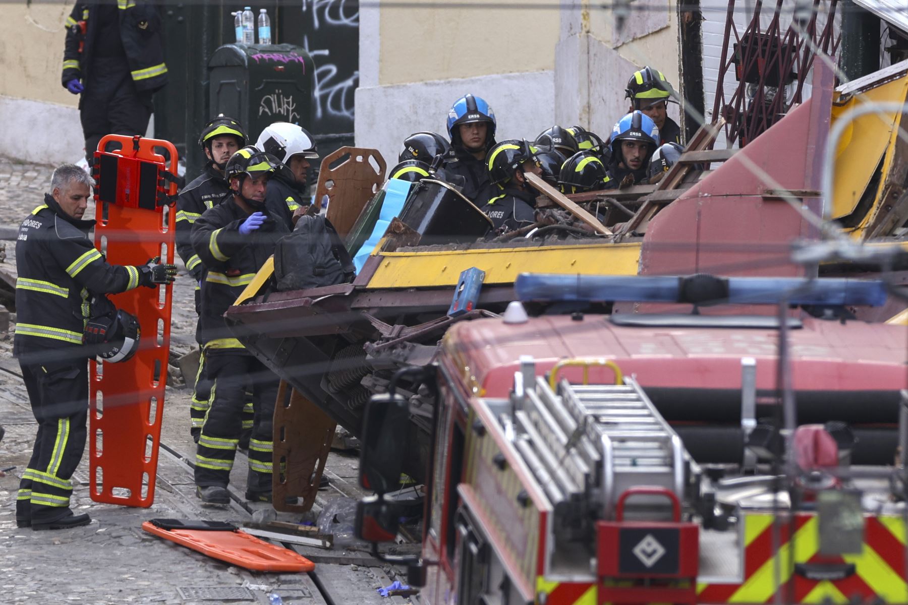 Rescatistas y bomberos trabajan en el lugar del descarrilamiento del funicular Gloria en Lisboa, Portugal. Foto: EFE