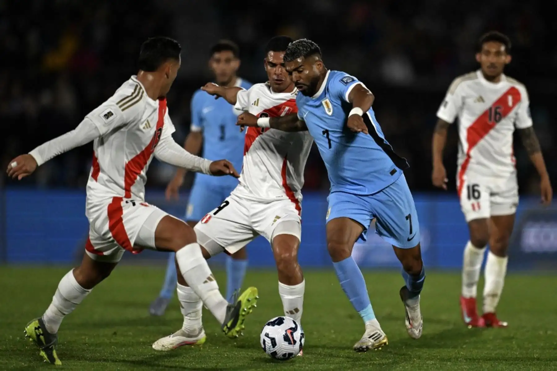 El delantero uruguayo Rodrigo Aguirre lucha por el balón con los defensas peruanos Marcos López y Erick Noriega. Foto: AFP