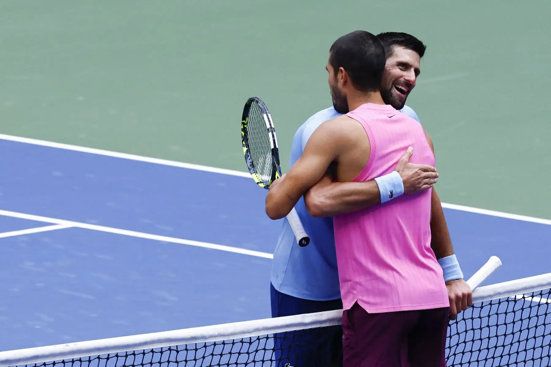 El español Carlos Alcaraz y el serbio Novak Djokovic se abrazan en la red después de la victoria de Alcaraz en su partido de semifinales de tenis individual masculino en el día trece del torneo de tenis US Open en el Centro Nacional de Tenis Billie Jean King de la USTA en Nueva York el 5 de septiembre de 2025. Foto: AFP