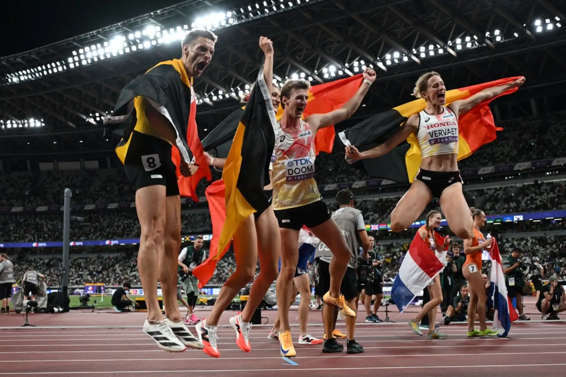 Dylan Borlee, Alexander Doom y Imke Vervaet de Bélgica celebran con la bandera de su país tras culminar su participación en la final del relevo mixto 4x400m durante el Campeonato Mundial de Atletismo en Tokio el 13 de septiembre de 2025. Foto: AFP
