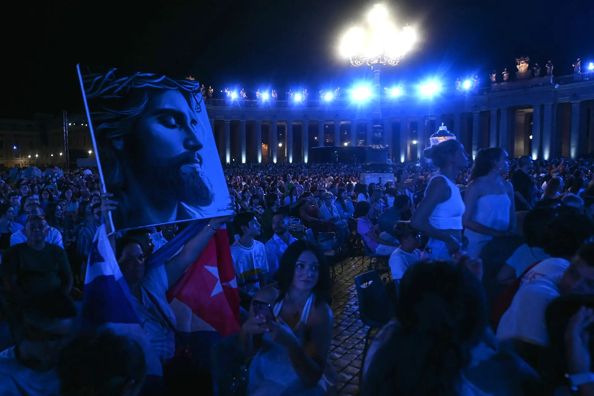 Una mujer levanta un retrato de Jesucristo durante el concierto gratuito "Gracia para el Mundo" y el espectáculo de luces en la Plaza de San Pedro del Vaticano.
Foto: AFP