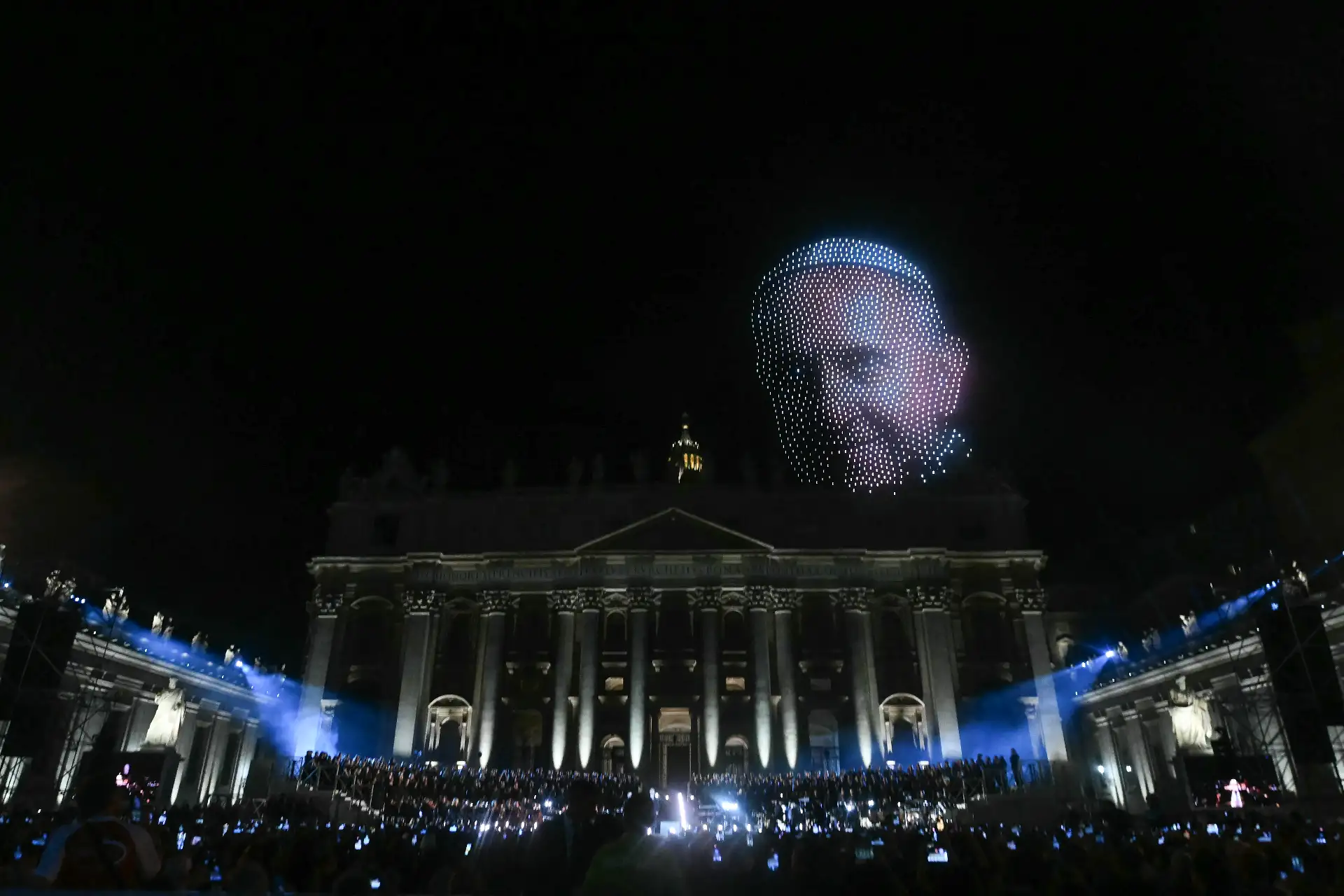 La gente observa cómo se crea un retrato del papa Francisco con drones durante el concierto gratuito "Gracia para el Mundo" y el espectáculo de luces en la Plaza de San Pedro del Vaticano.
Foto: AFP