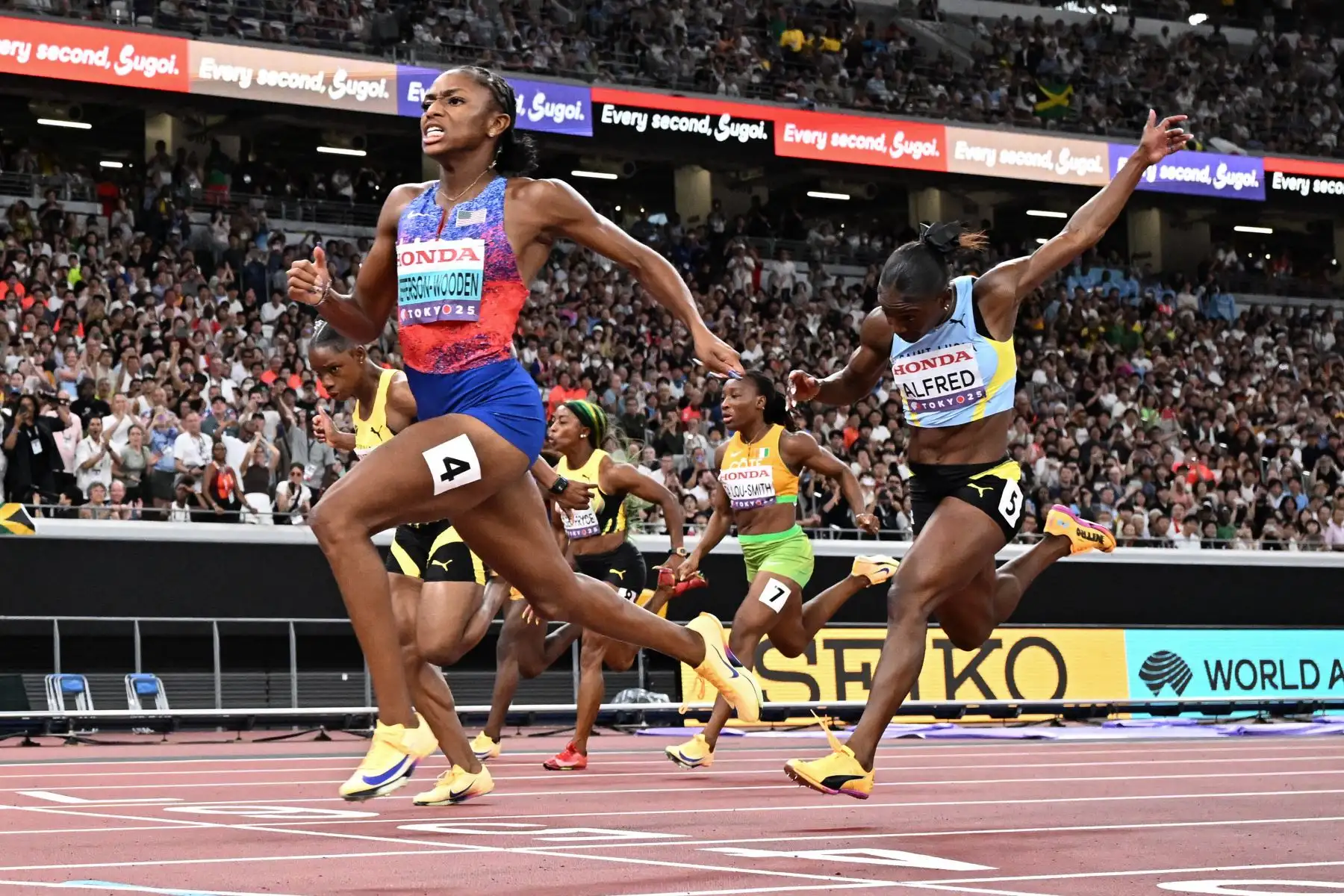 La estadounidense Melissa Jefferson cruza la línea de meta para ganar mientras compite en la final femenina de 100 metros junto al atleta de Santa Lucía, Julien Alfred, durante el Campeonato Mundial de Atletismo en Tokio el 14 de septiembre de 2025. Foto: AFP