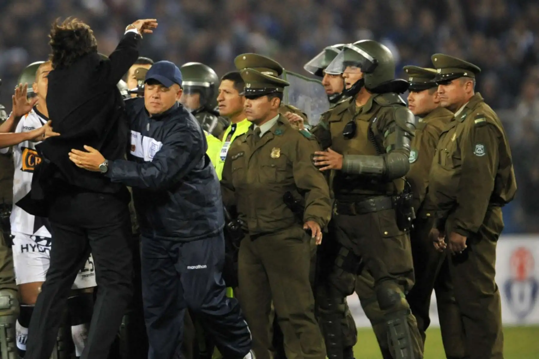 El entrenador de Alianza Lima de Perú, Jorge Costas, intenta alcanzar al árbitro Carlos Alfredo Vera, protegido por policías, durante los incidentes en el partido de la Copa Libertadores entre Alianza y Universidad de Chile, el 6 de mayo de 2010. Foto: AFP