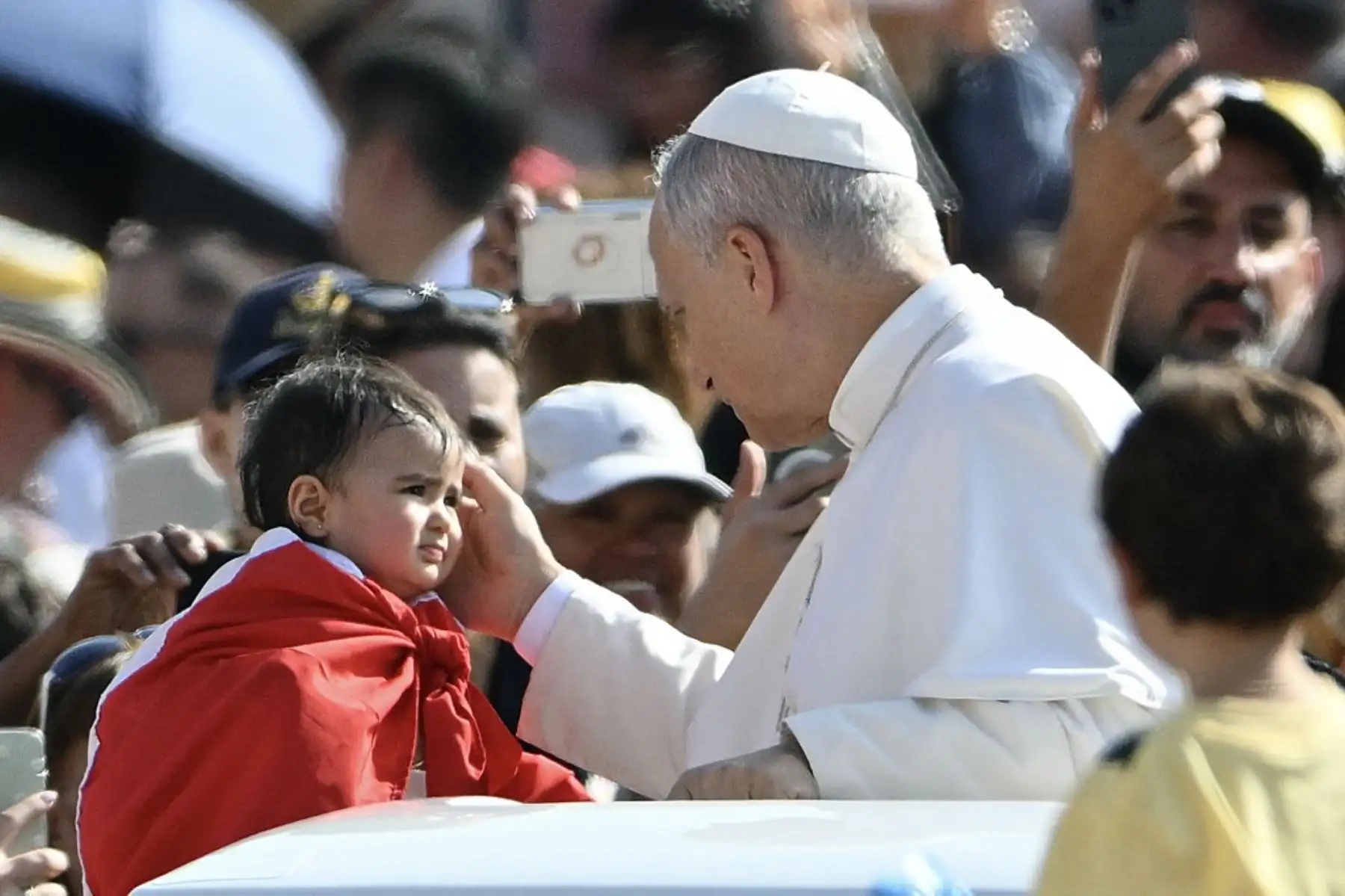 El papa León XIV bendice a un niño pequeño al llegar en el papamóvil para presidir su audiencia general semanal en la plaza de San Pedro del Vaticano. Foto: AFP