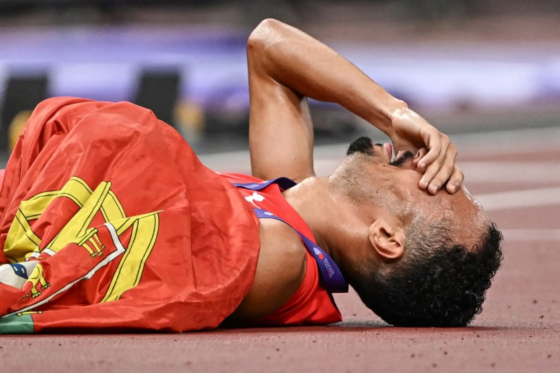El atleta portugués Isaac Nader celebra con la bandera de su país tras ganar la final masculina de 1500 m durante el Campeonato Mundial de Atletismo en Tokio. Foto: AFP