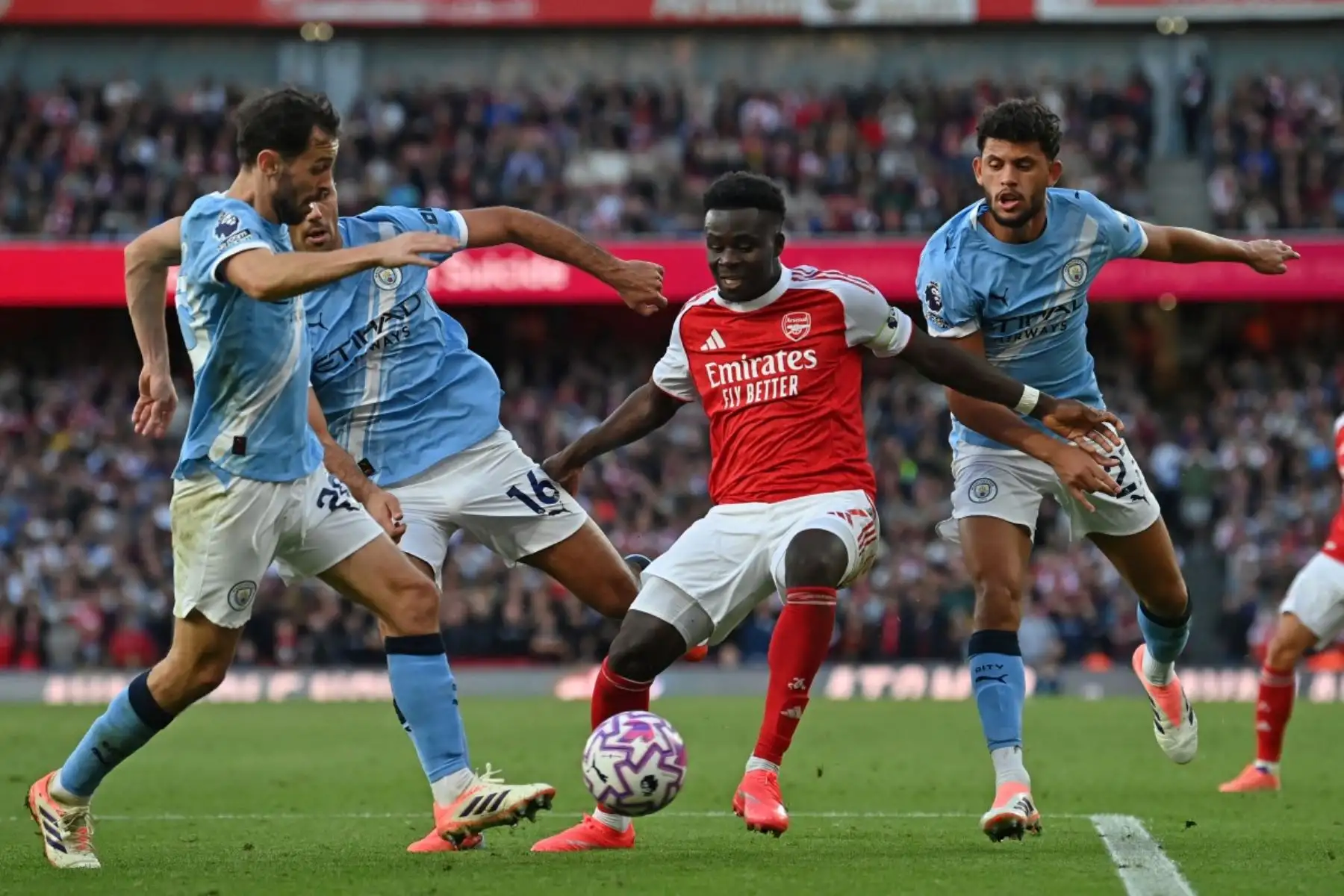 El centrocampista inglés del Arsenal, Bukayo Saka, compite por el balón contra tres jugadores del Manchester City durante el partido de fútbol de la Premier League inglesa entre Arsenal y Manchester City en el Emirates Stadium en Londres el 21 de septiembre de 2025. Foto: AFP
