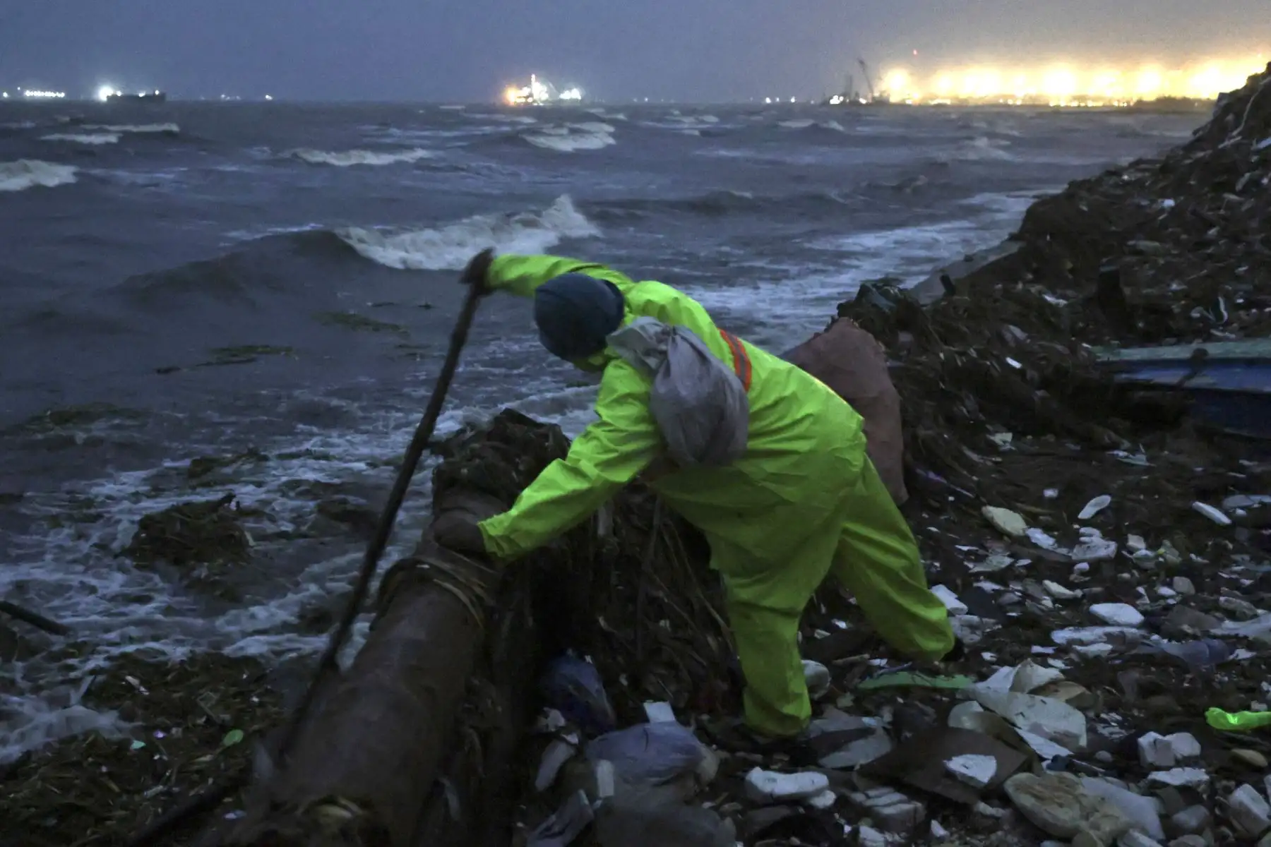 Un hombre filipino recoge materiales reciclables en la costa de Manila, Filipinas, el 22 de septiembre de 2025. La oficina meteorológica filipina recomendó a los residentes mantenerse alerta ante posibles inundaciones y deslizamientos de tierra causados ​​por el supertifón Ragasa. Foto: AFP