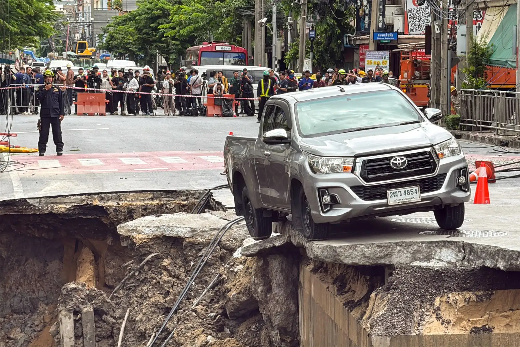 La gente observa un vehículo al borde del agujero en el suelo de 50 metros de profundidad después de que una carretera se derrumbara cerca de un hospital en Bangkok, Tailandia, el 24 de septiembre de 2025. Foto: AFP