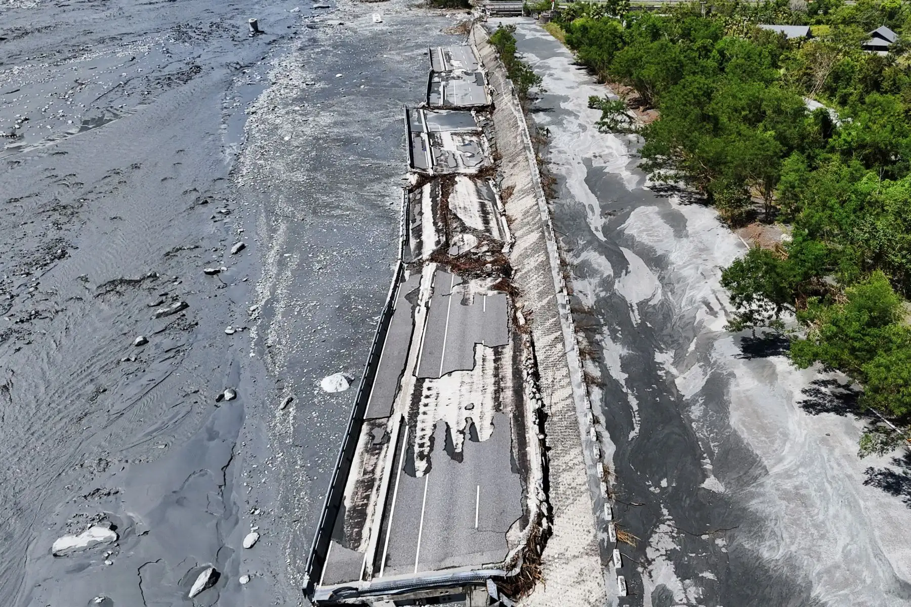 Lodo fluyendo y partes del puente dañado tras el desbordamiento de un lago barrera sobre el arroyo Mataian en Hualien. El desbordamiento del lago barrera en Taiwán causó al menos 14 muertos. Foto: AFP