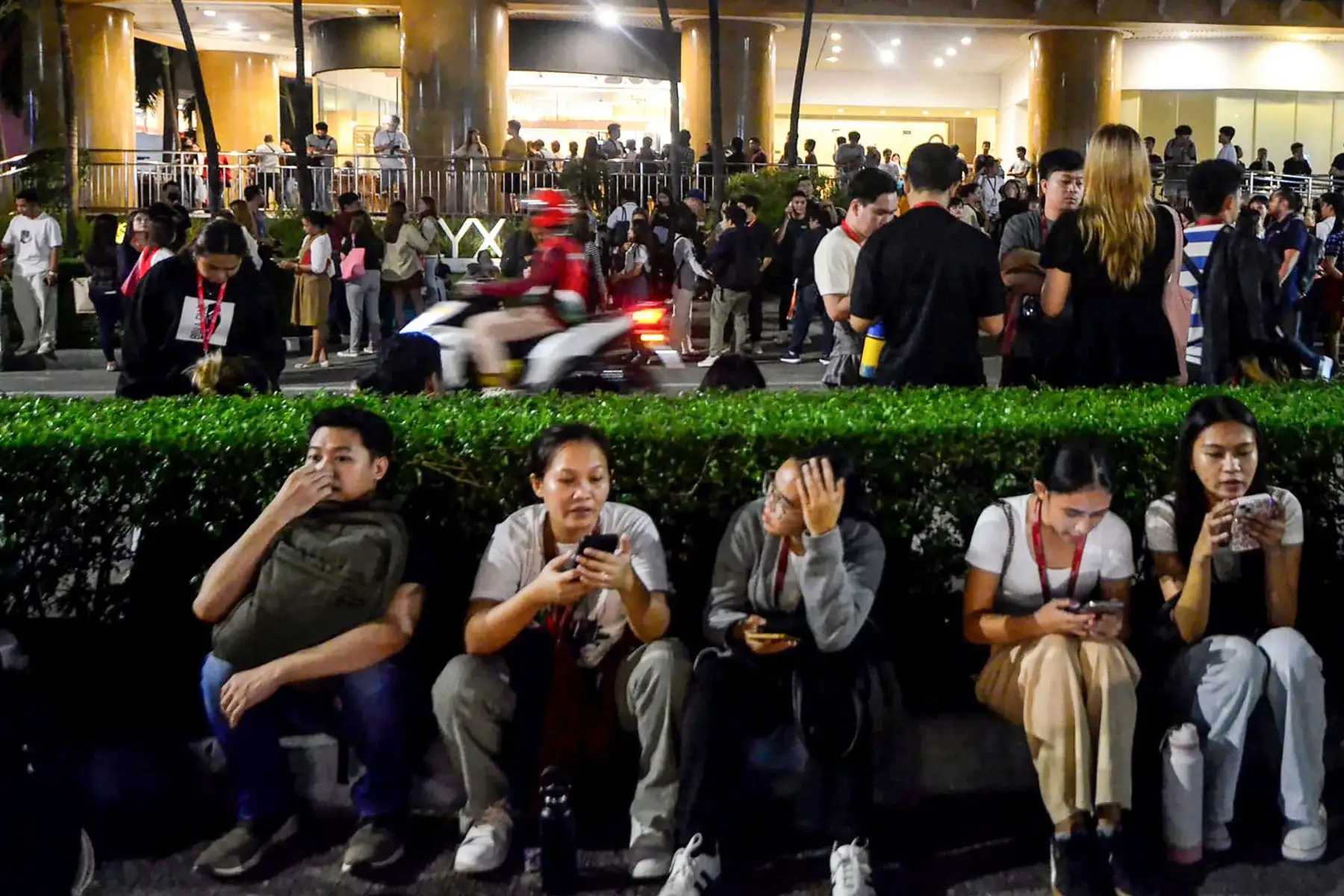 Los empleados de un centro de llamadas navegan por sus teléfonos móviles mientras se reúnen frente a su edificio de oficinas tras el terremoto en Cebú, en el centro de Filipinas.
Foto: AFP
