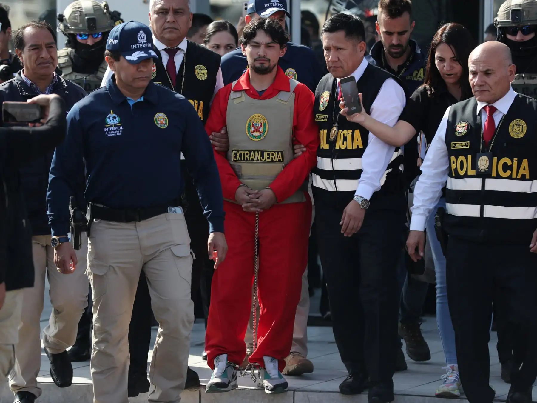 Matías Agustín Ozorio (c), de nacionalidad argentina, es trasladado por integrantes de la Policía Nacional de Perú (PNP) y de Interpol para ser entregado a la Policía Argentina este jueves, en la Base Aérea de Policía Aérea de Perú en Lima (Perú). La PNP entregó a la Policía de Argentina a Ozorio, señalado como presunto cómplice del peruano Tony Janzen Valverde (