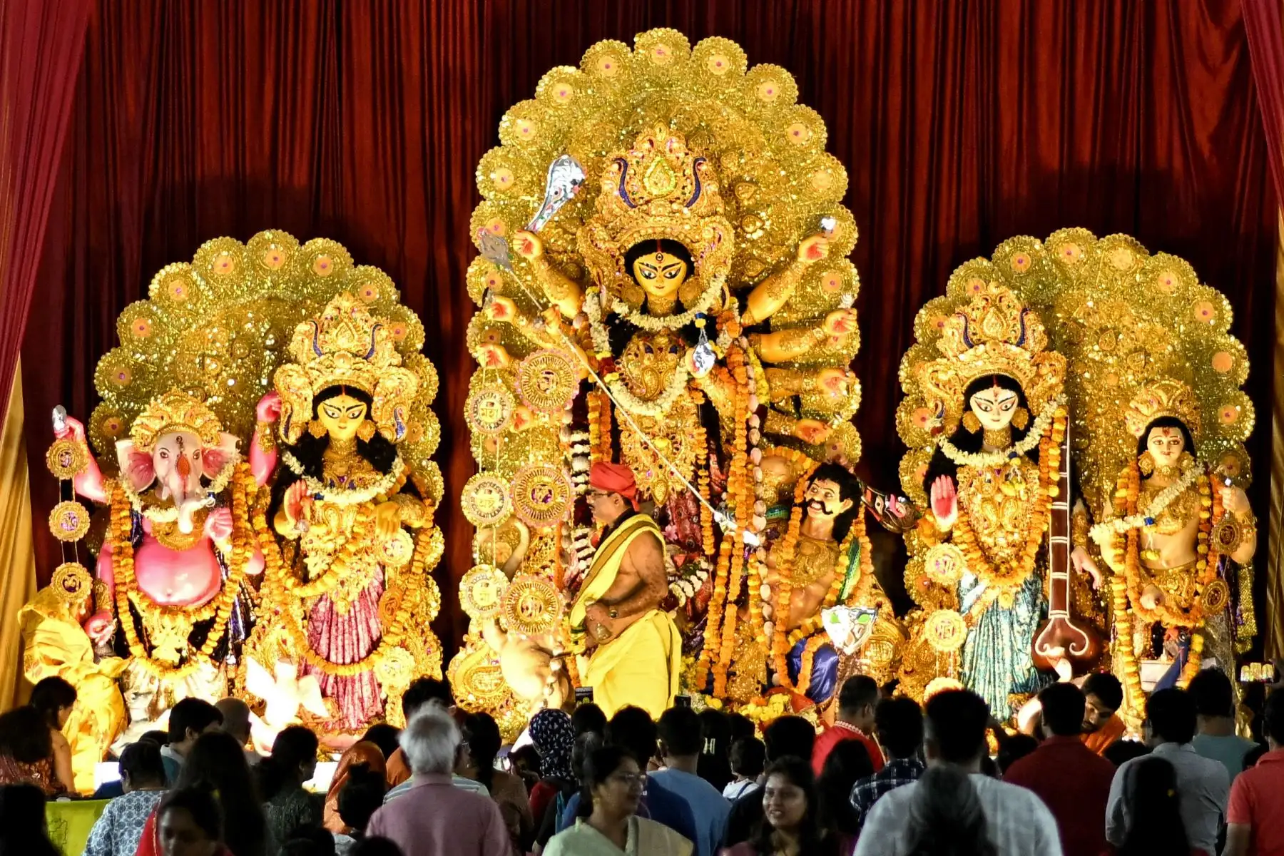 Los devotos observan a un sacerdote realizar rituales religiosos frente a un ídolo de la diosa hindú Durga en un lugar de culto temporal conocido como 