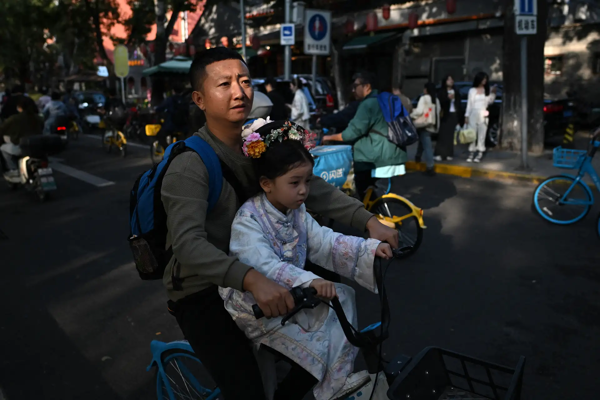Un hombre anda en bicicleta con una niña vestida con un traje tradicional chino en una calle de Pekín durante la Semana Dorada del Día Nacional de China.
Foto: AFP