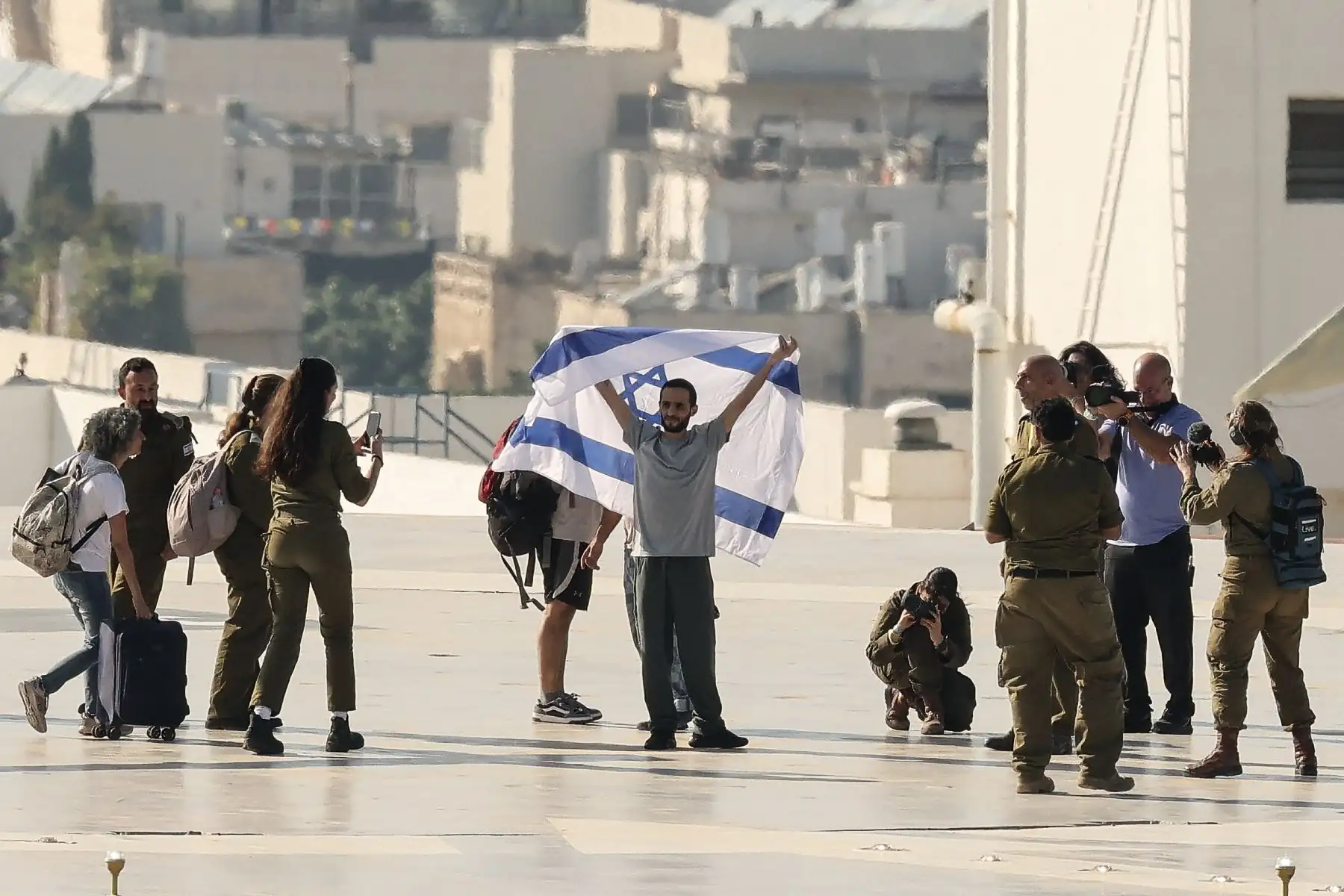 El exrehén israelí Nimrod Cohen, quien permaneció cautivo en Gaza desde los ataques del 7 de octubre de 2023 perpetrados por militantes palestinos, ondea una bandera israelí al desembarcar de un helicóptero militar israelí en la plataforma de aterrizaje del Centro Médico Ichilov Sourasky en Tel Aviv el 13 de octubre de 2025. Foto: AFP