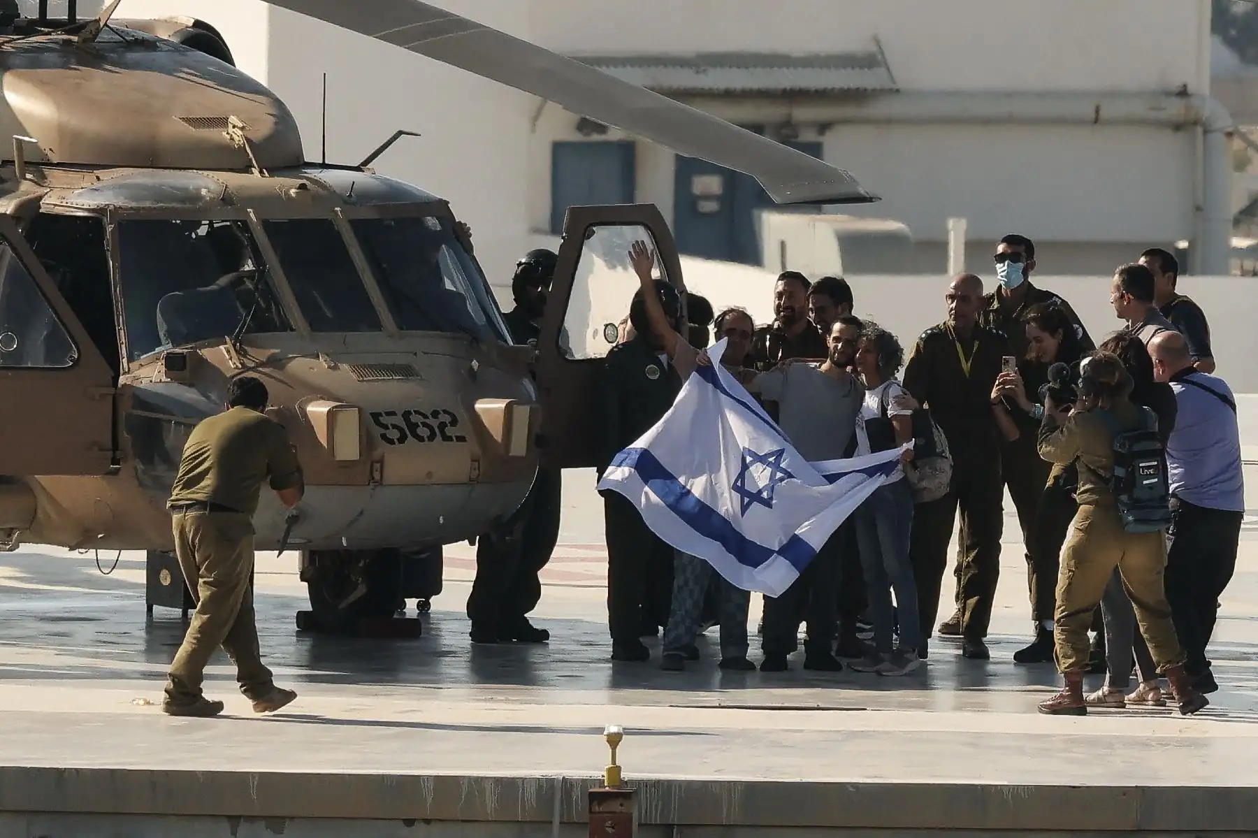 El exrehén israelí Nimrod Cohen, quien permaneció cautivo en Gaza desde los ataques del 7 de octubre de 2023 perpetrados por militantes palestinos, ondea una bandera israelí al desembarcar de un helicóptero militar israelí en la plataforma de aterrizaje del Centro Médico Ichilov Sourasky en Tel Aviv el 13 de octubre de 2025. Foto: AFP