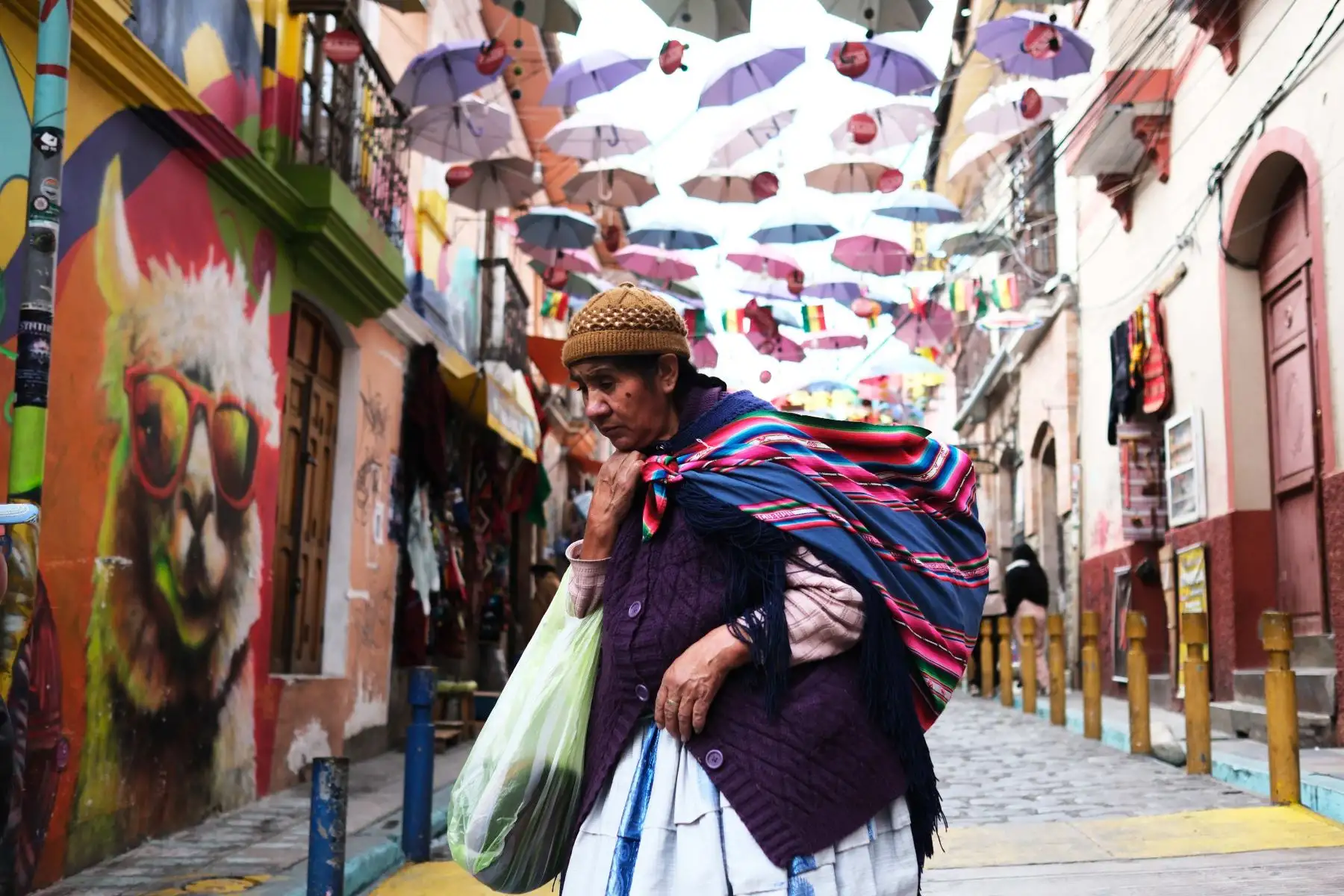 Una mujer aimara camina por una calle turística este sábado en La Paz. Los bolivianos volverán a las urnas este domingo para elegir por primera vez en su historia a su presidente y vicepresidente en una segunda vuelta que disputarán el senador centrista Rodrigo Paz y el exmandatario conservador Jorge Quiroga y que también supondrá un nuevo ciclo político y económico tras 20 años de la izquierda en el poder. 
Foto: EFE