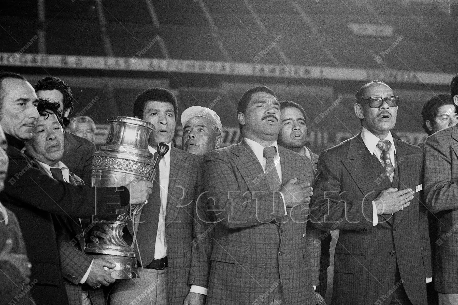 Lima - 30 octubre 1975 / Héctor Chumpitaz, con la Copa América, y Marcos Calderón cantan el Himno Nacional. La selección peruana de fútbol recibió un multitudinario homenaje tras obtener el título de campeón sudamericano de fútbol al vencer a Colombia por 1-0 en Caracas.  Foto: Archivo Histórico de El Peruano / Humberto Romaní Lima - 30 octubre 1975 / Héctor Chumpitaz, con la Copa América, y Marcos Calderón cantan el Himno Nacional. La selección peruana de fútbol recibió un multitudinario homenaje tras obtener el título de campeón sudamericano de fútbol al vencer a Colombia por 1-0 en Caracas.  Foto: Archivo Histórico de El Peruano / Humberto Romaní