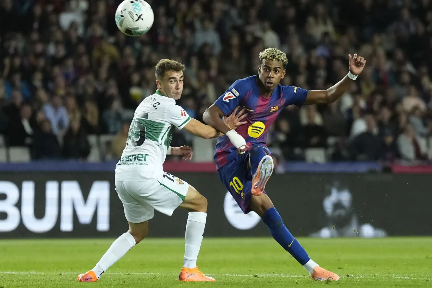 El delantero del Barcelona Lamine Yamal (d) dispara a puerta durante el partido de LaLiga entre el FC Barcelona y el Elche CF, este domingo en el estadio Olímpico Lluis Companys. EFE/Enric Fontcuberta