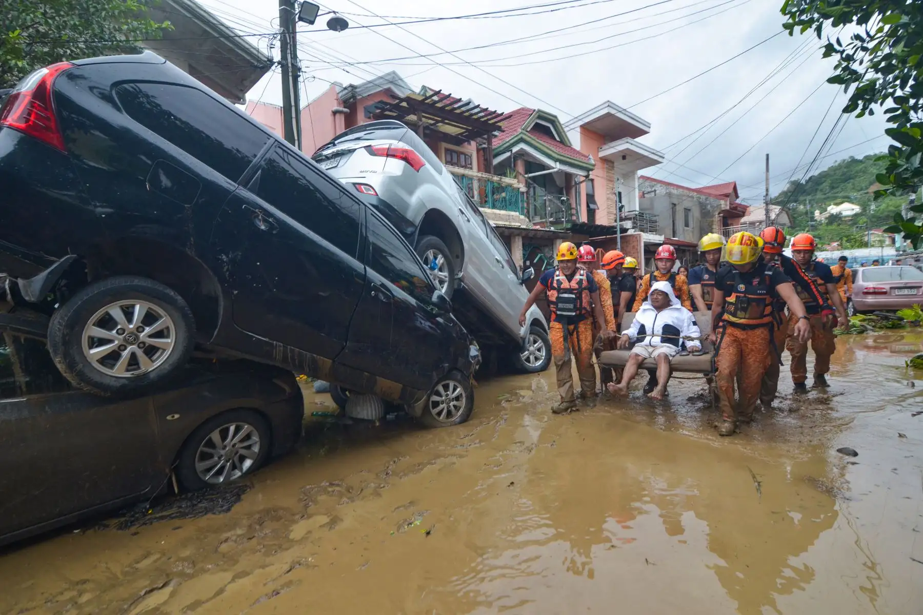 Rescatistas trasladan a un residente entre autos arrastrados por las inundaciones durante el punto álgido del tifón Kalmaegi en una subdivisión de la ciudad de Cebú, en el centro de Filipinas. Foto: AFP