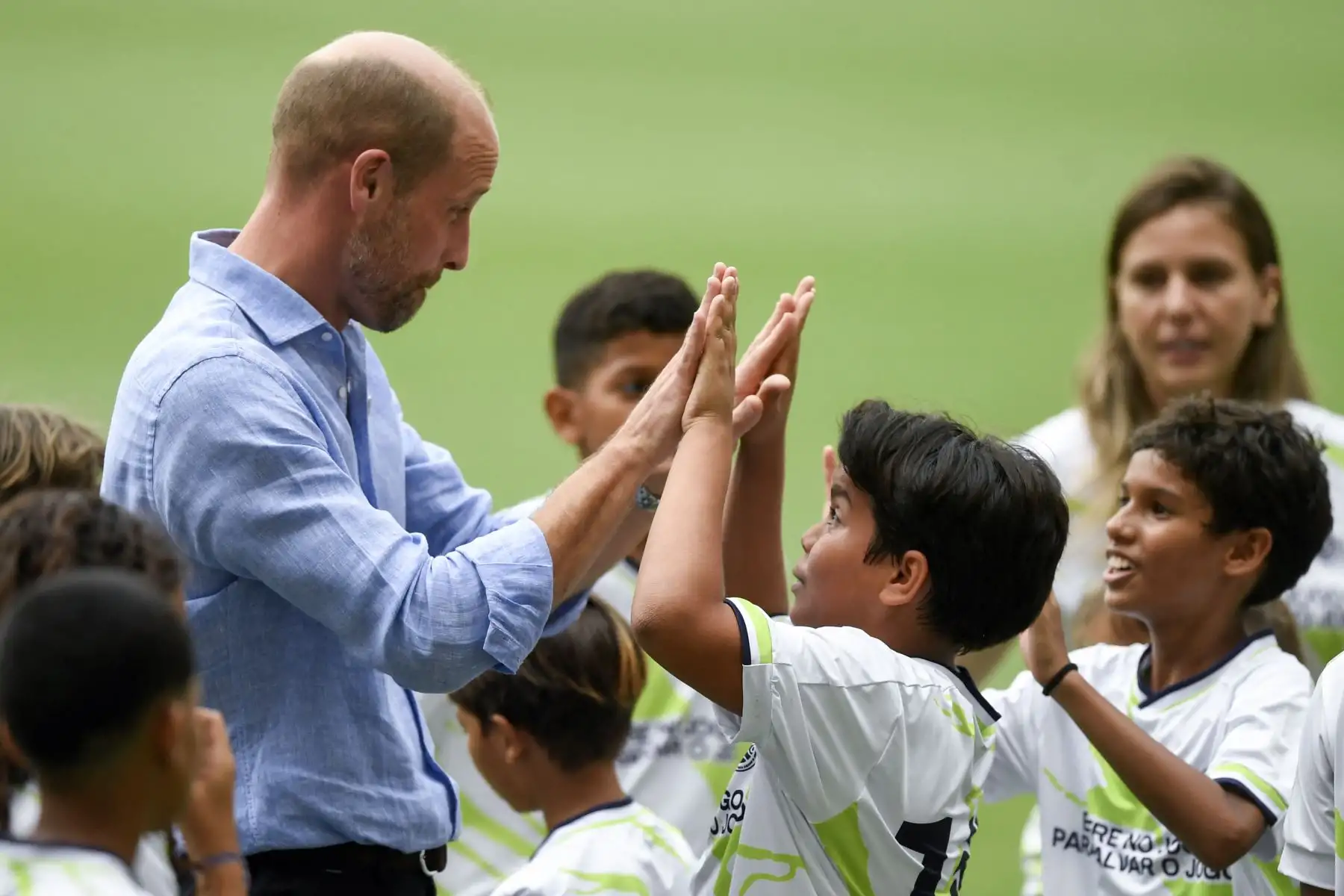 El príncipe Guillermo de Gran Bretaña, príncipe de Gales, choca los cinco con un niño que participa en proyectos sociales, durante el evento "Fútbol Comunitario" en el estadio Maracaná de Río de Janeiro. AFP