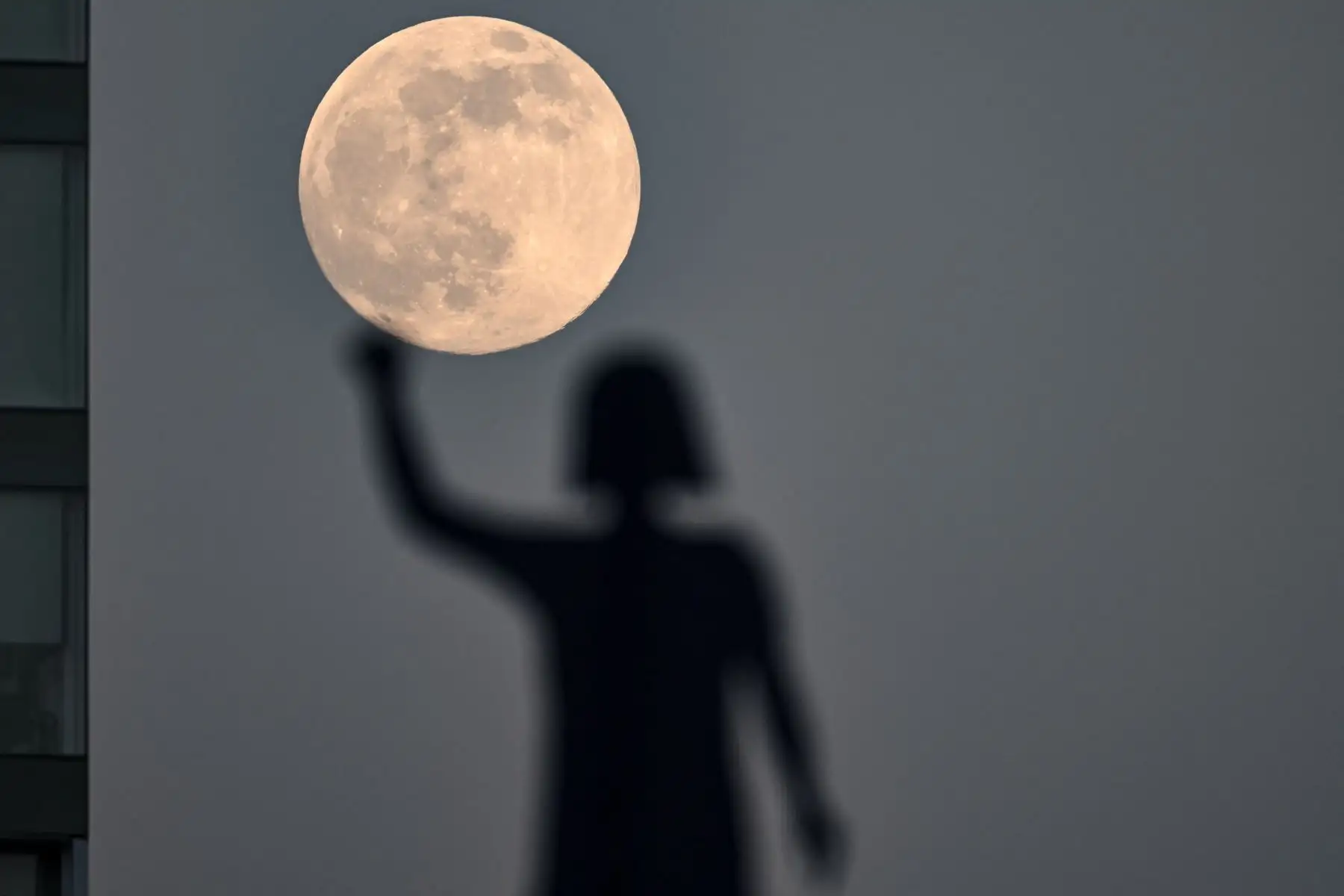 La superluna conocida como la Luna del Castor se ve detrás de la estatua dedicada a las "Mujeres que Luchan" en la Glorieta de las Mujeres en la Ciudad de México. Foto: AFP
